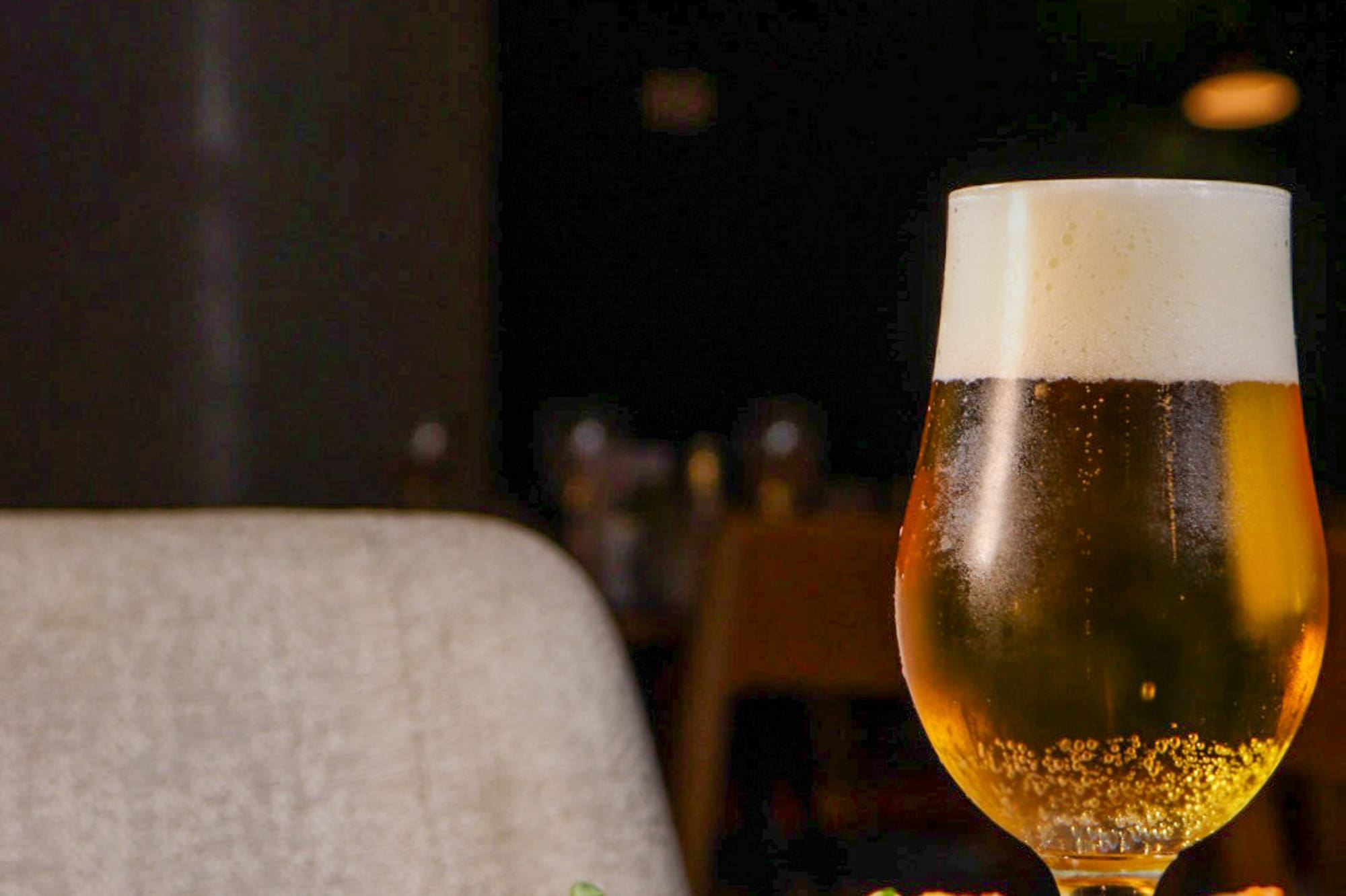 Cerveza rubia y aperitivos fritos con salsa en plato, ambiente de bar.