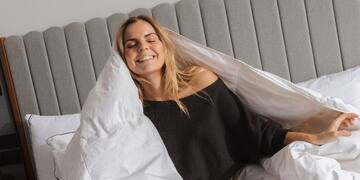 a woman sitting on a bed with a blanket covering her face