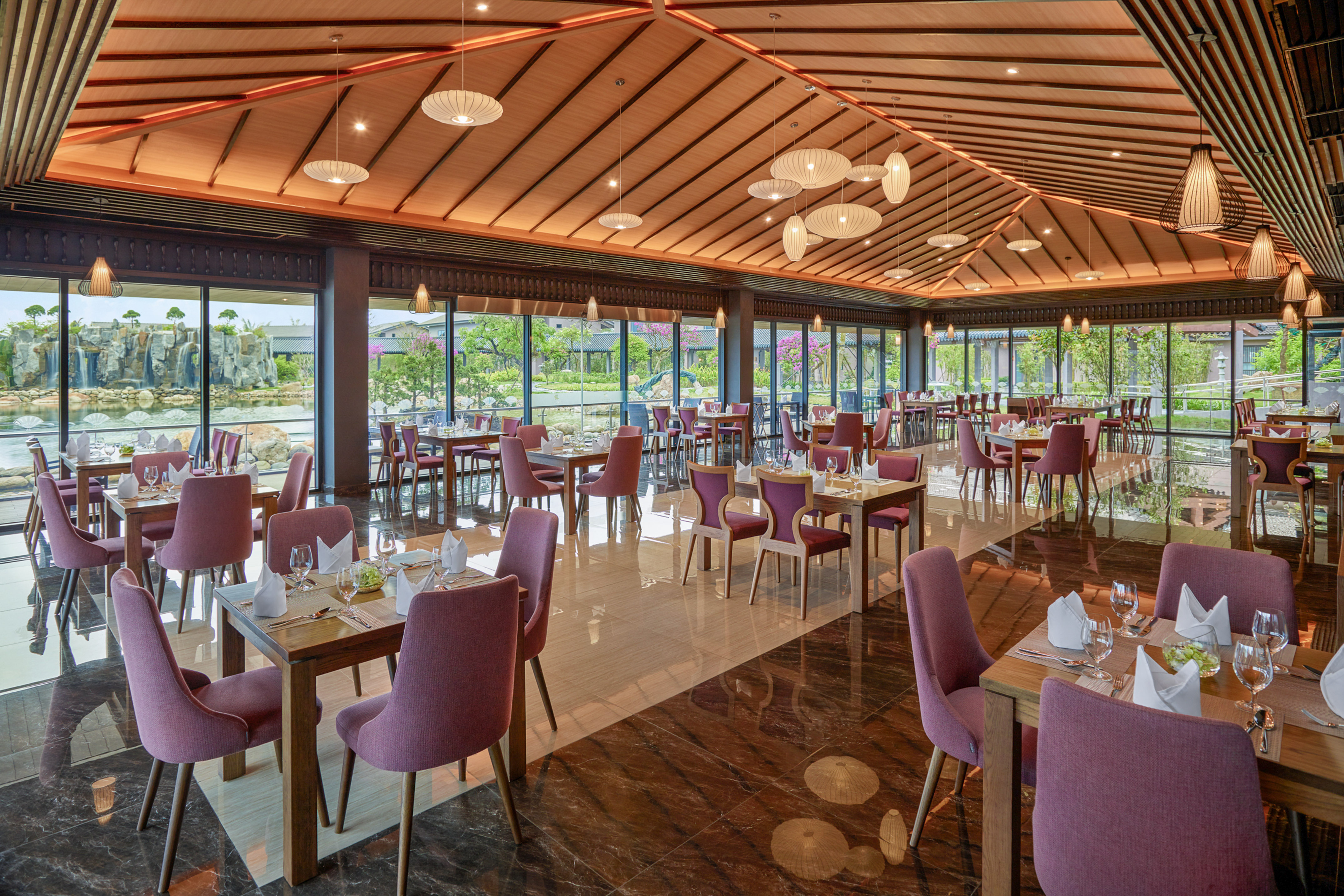 Modern dining room with purple chairs, wood ceiling, and scenic waterfall view.