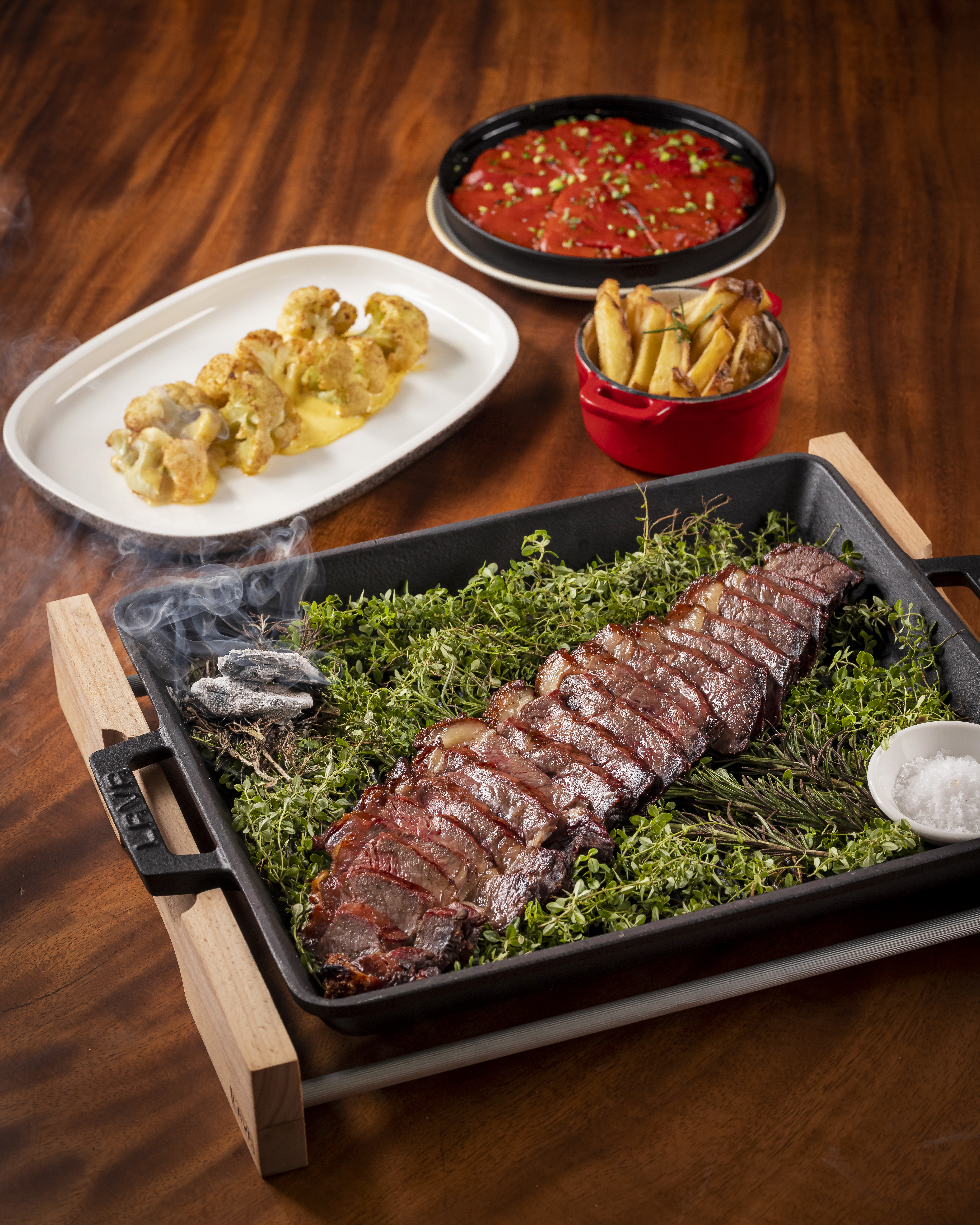 Smoking sliced steak on herbs, roasted cauliflower, fries, and red peppers.