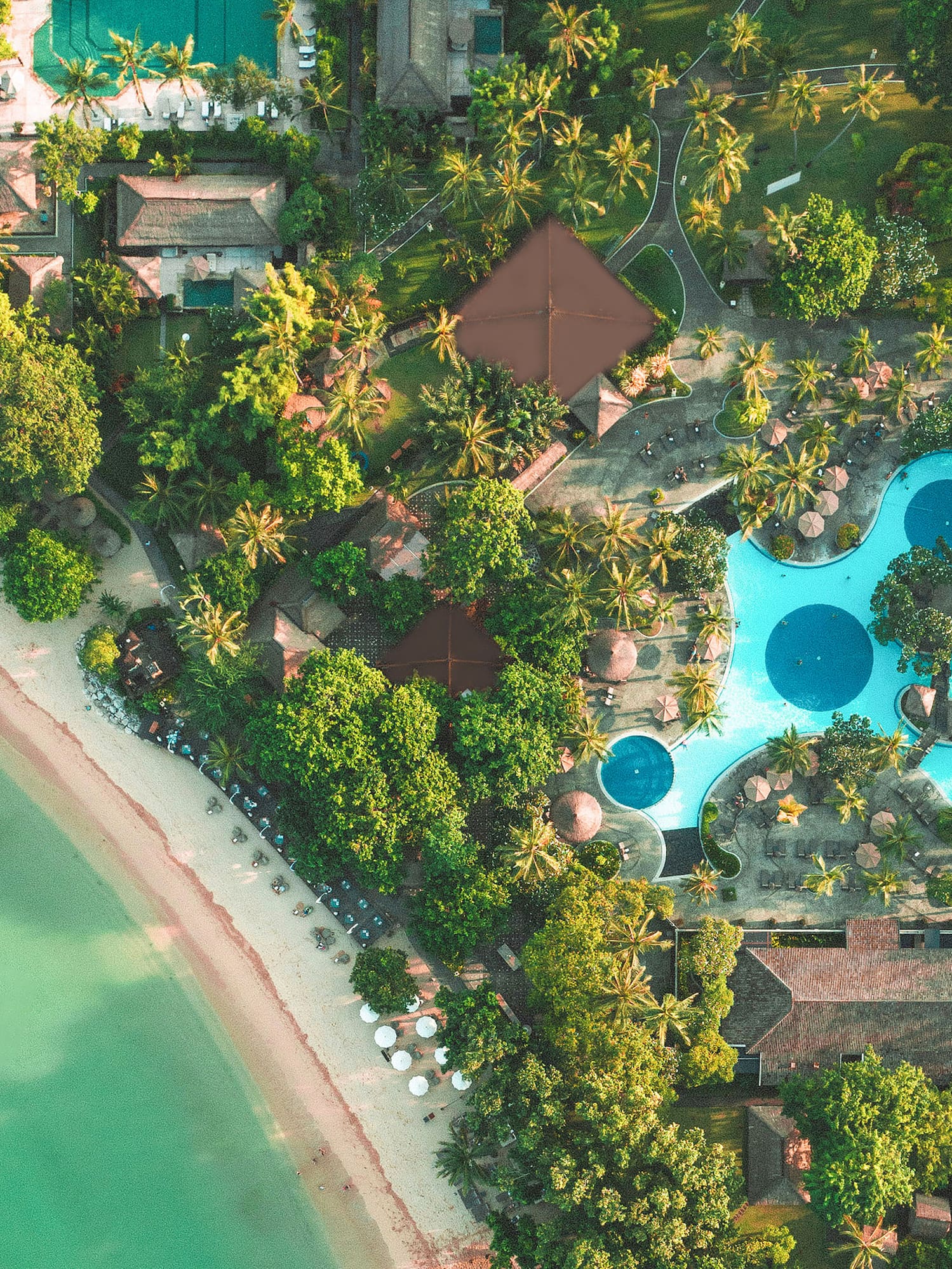 an aerial view of a resort with swimming pools and trees