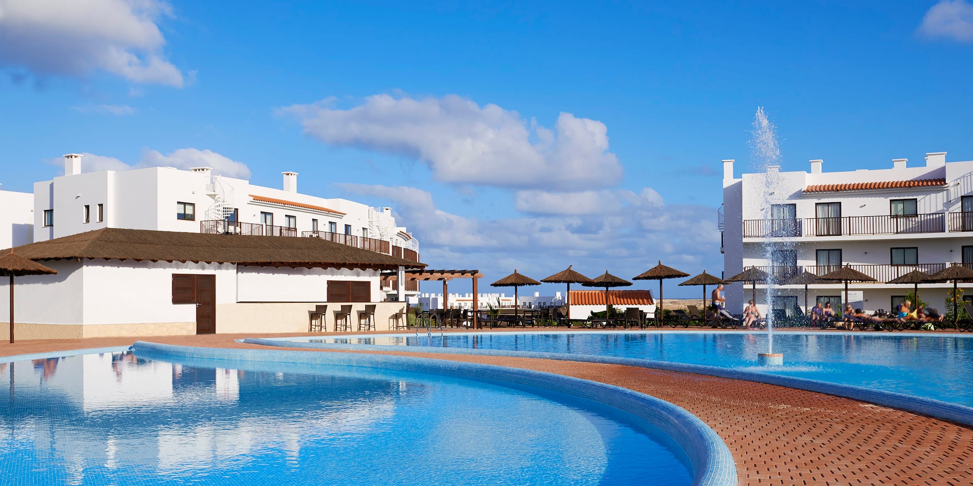 a pool with a fountain and buildings