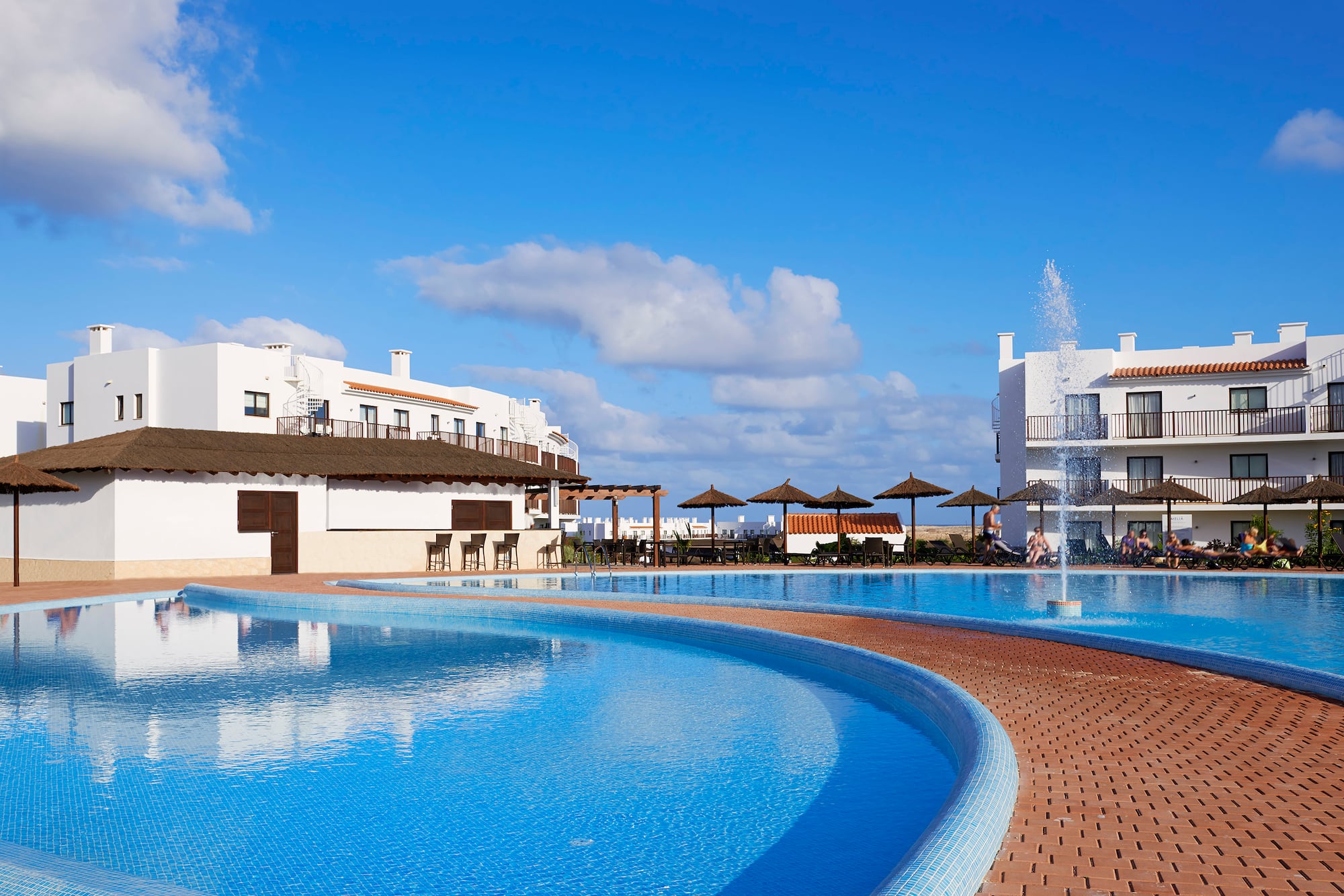 a pool with a fountain and buildings