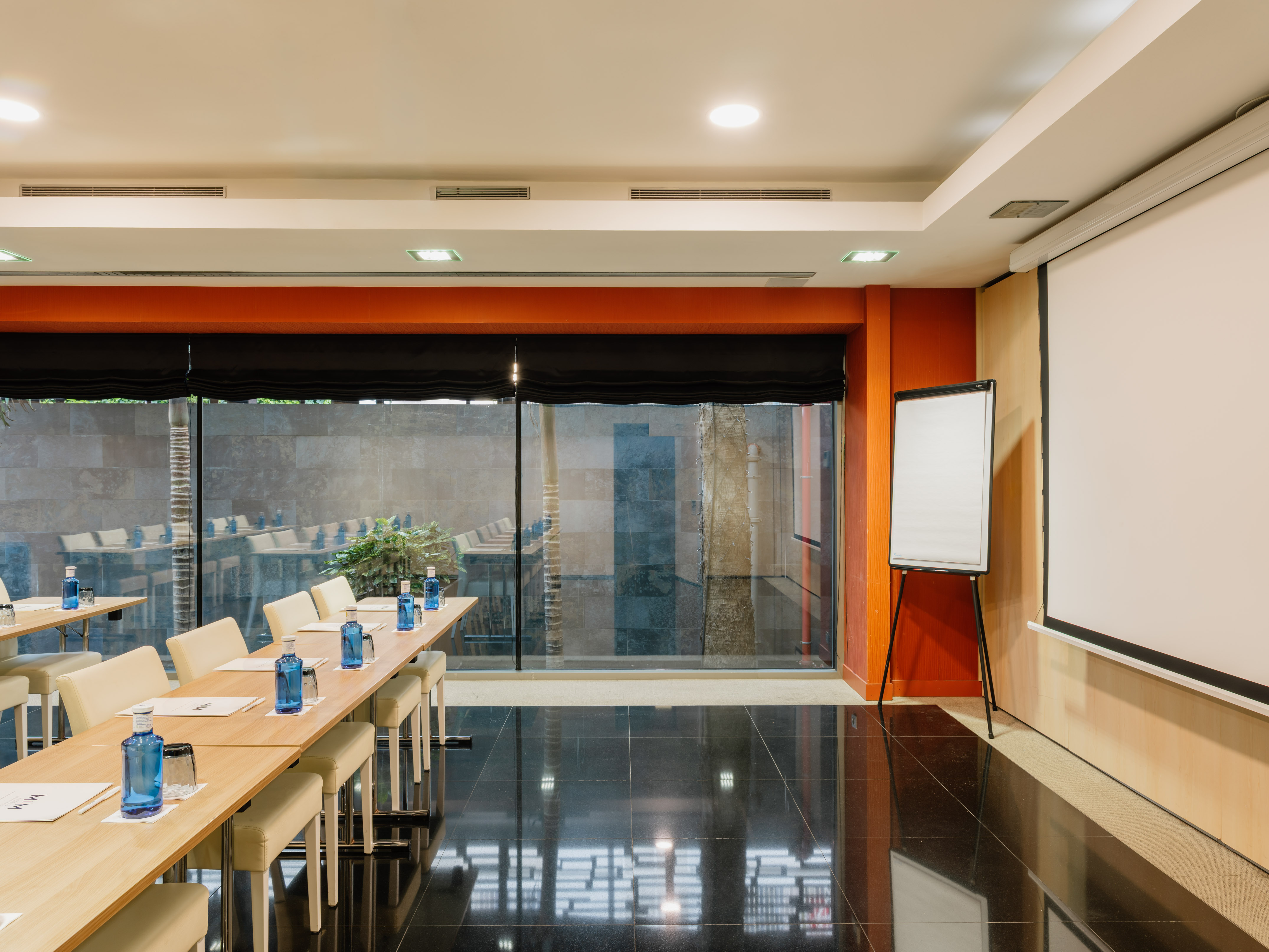 Modern conference room with presentation screen, tables, and water bottles.