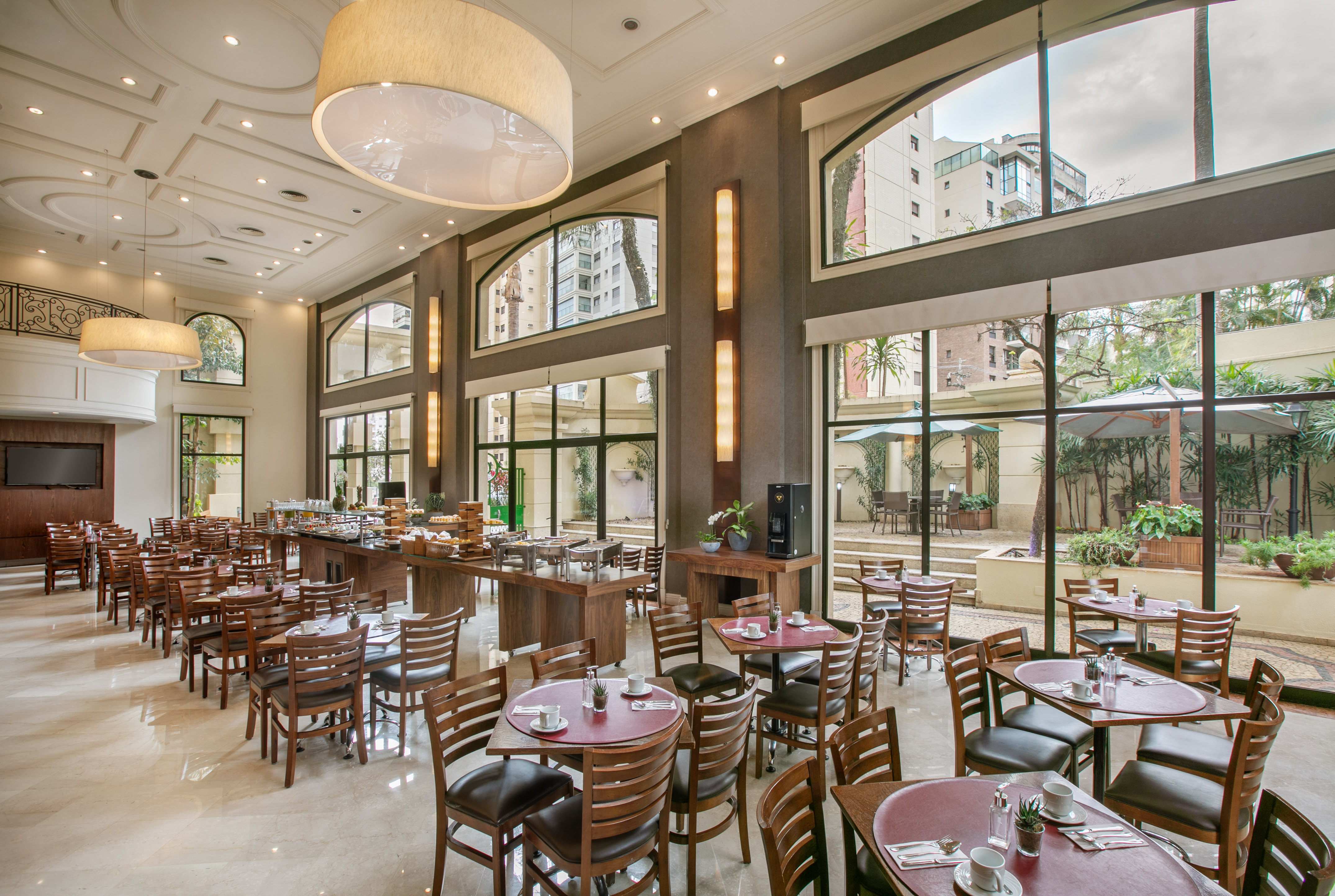 Spacious hotel restaurant with buffet, dining tables, and garden views.