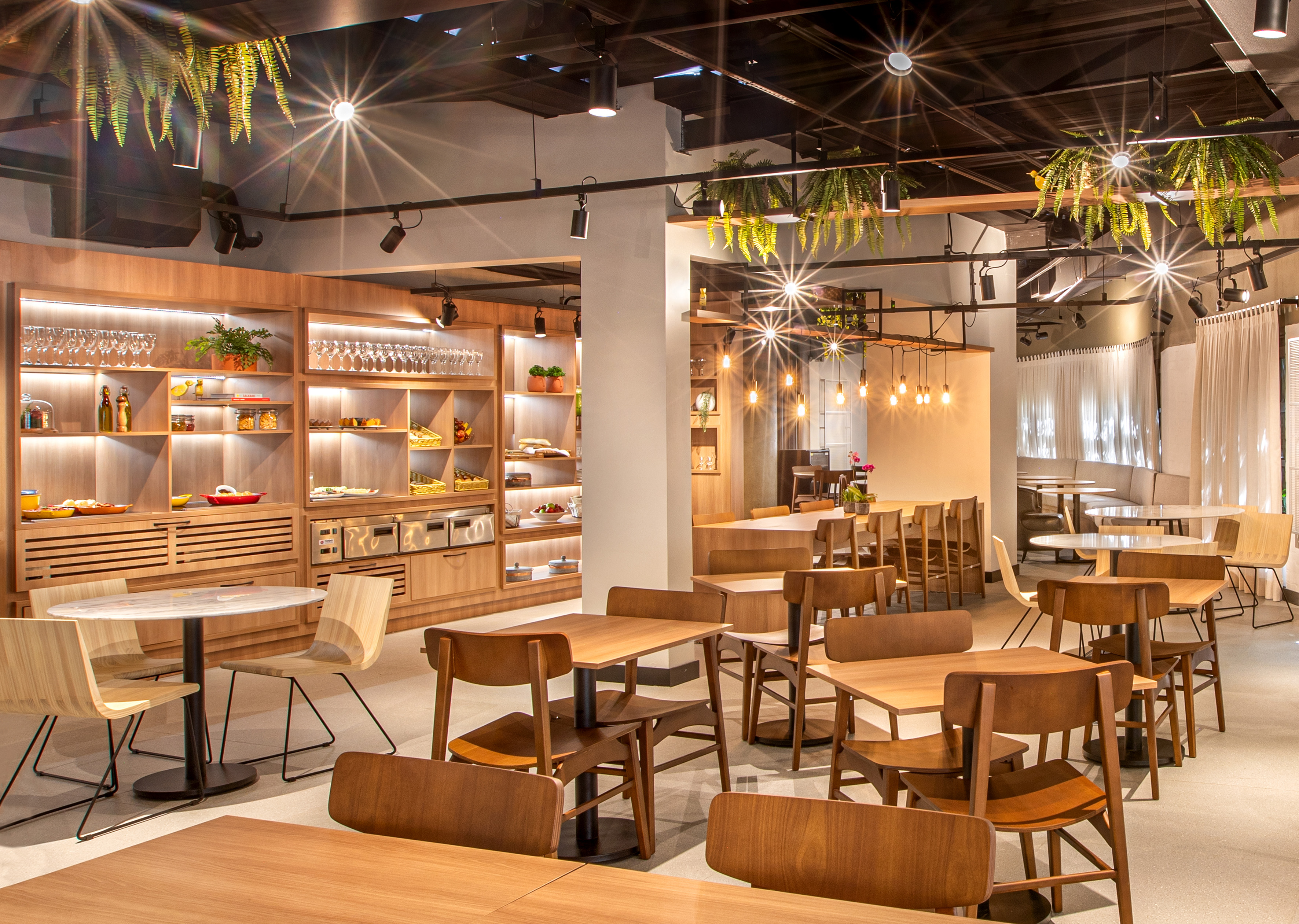 Modern restaurant dining area with wooden tables, buffet, and contemporary decor.