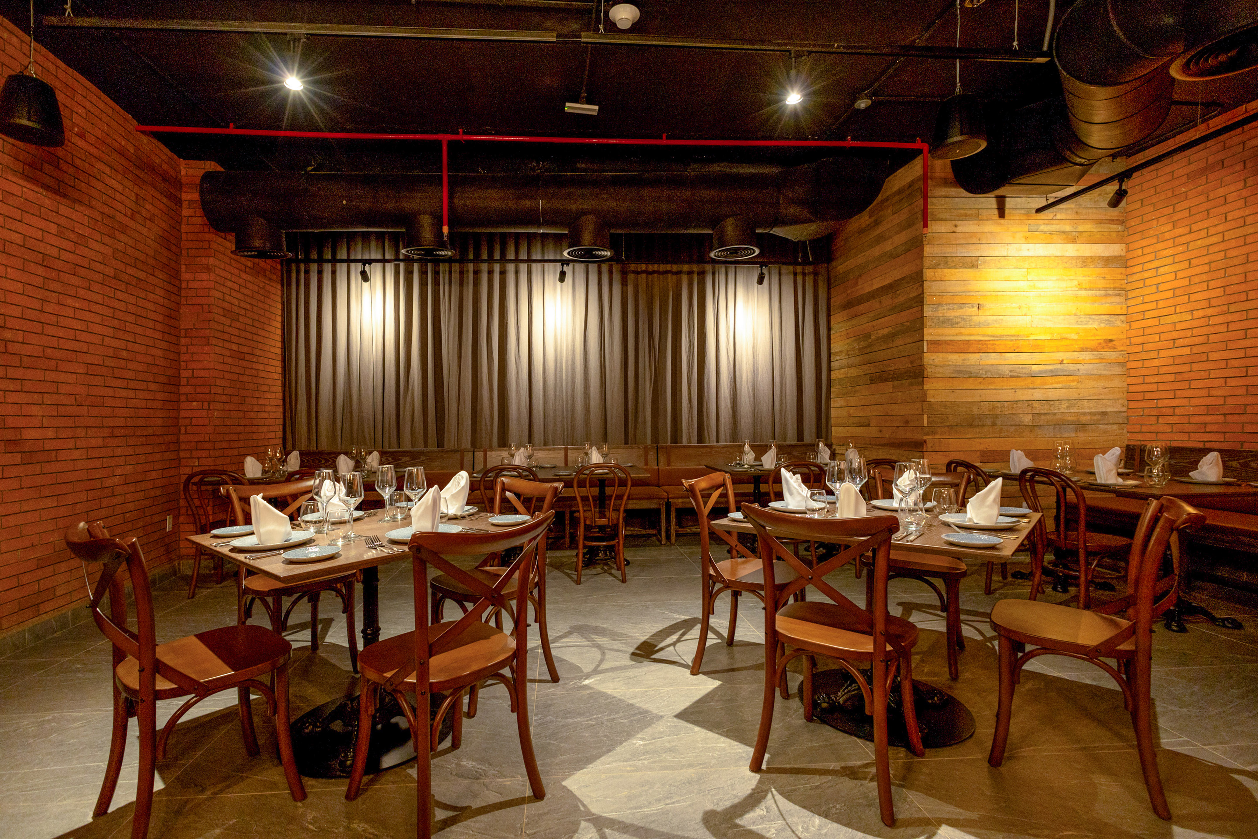 Modern restaurant with exposed brick, wooden tables, and industrial ceiling.