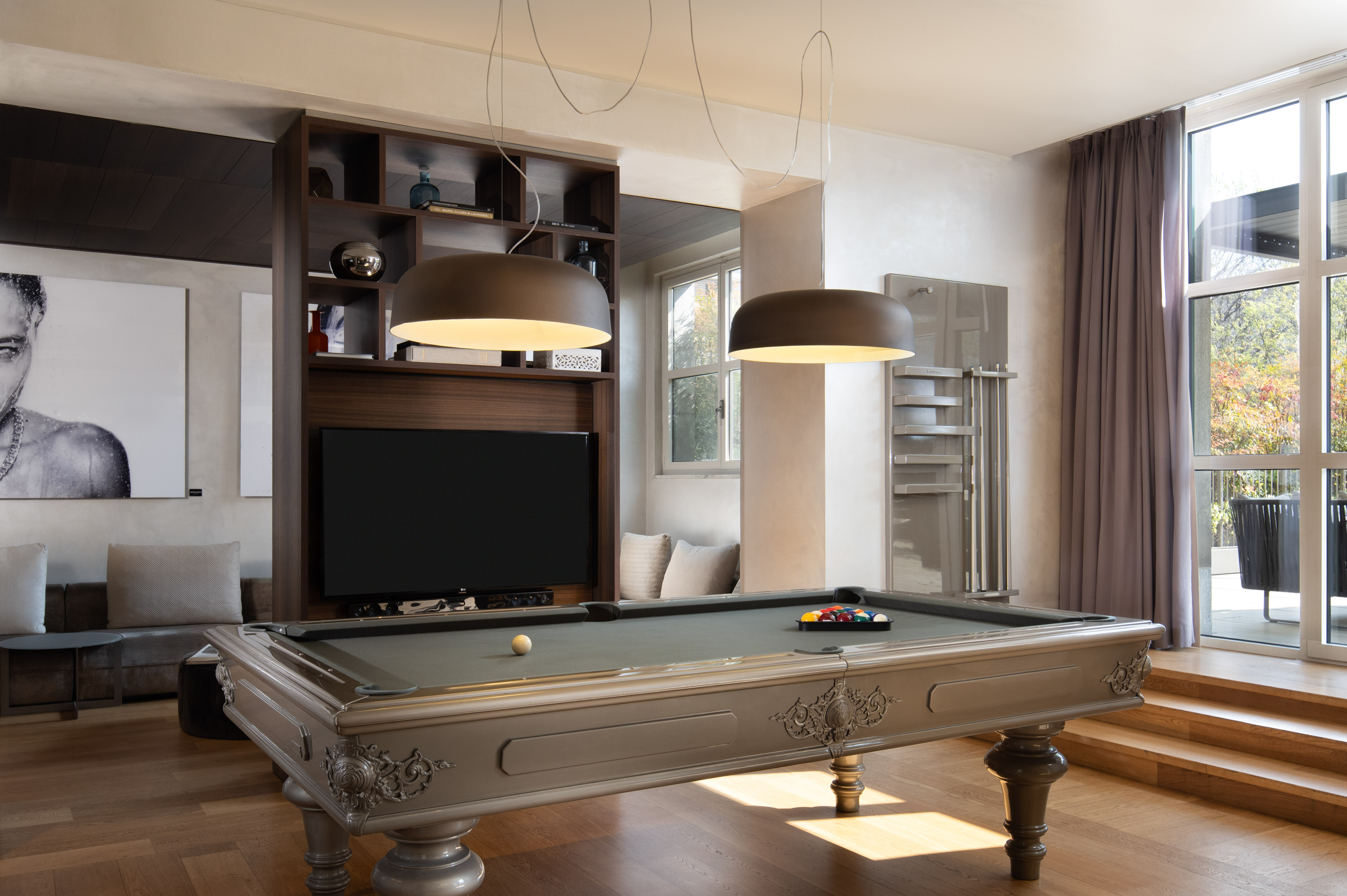 Luxurious game room with ornate pool table, large TV, and modern lighting.