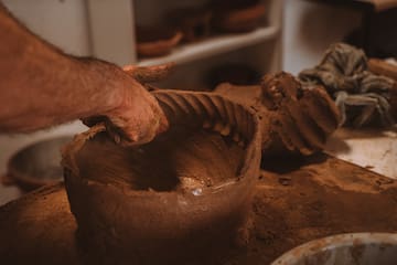 a person's hand holding a clay bowl