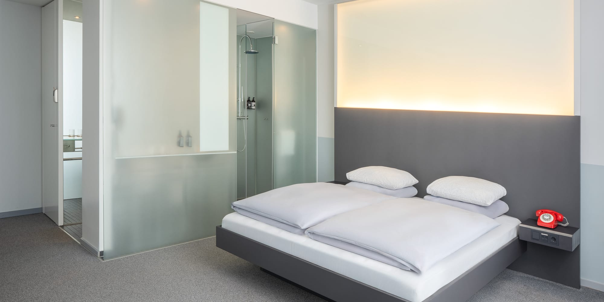 a bed with white sheets and a glass shower
