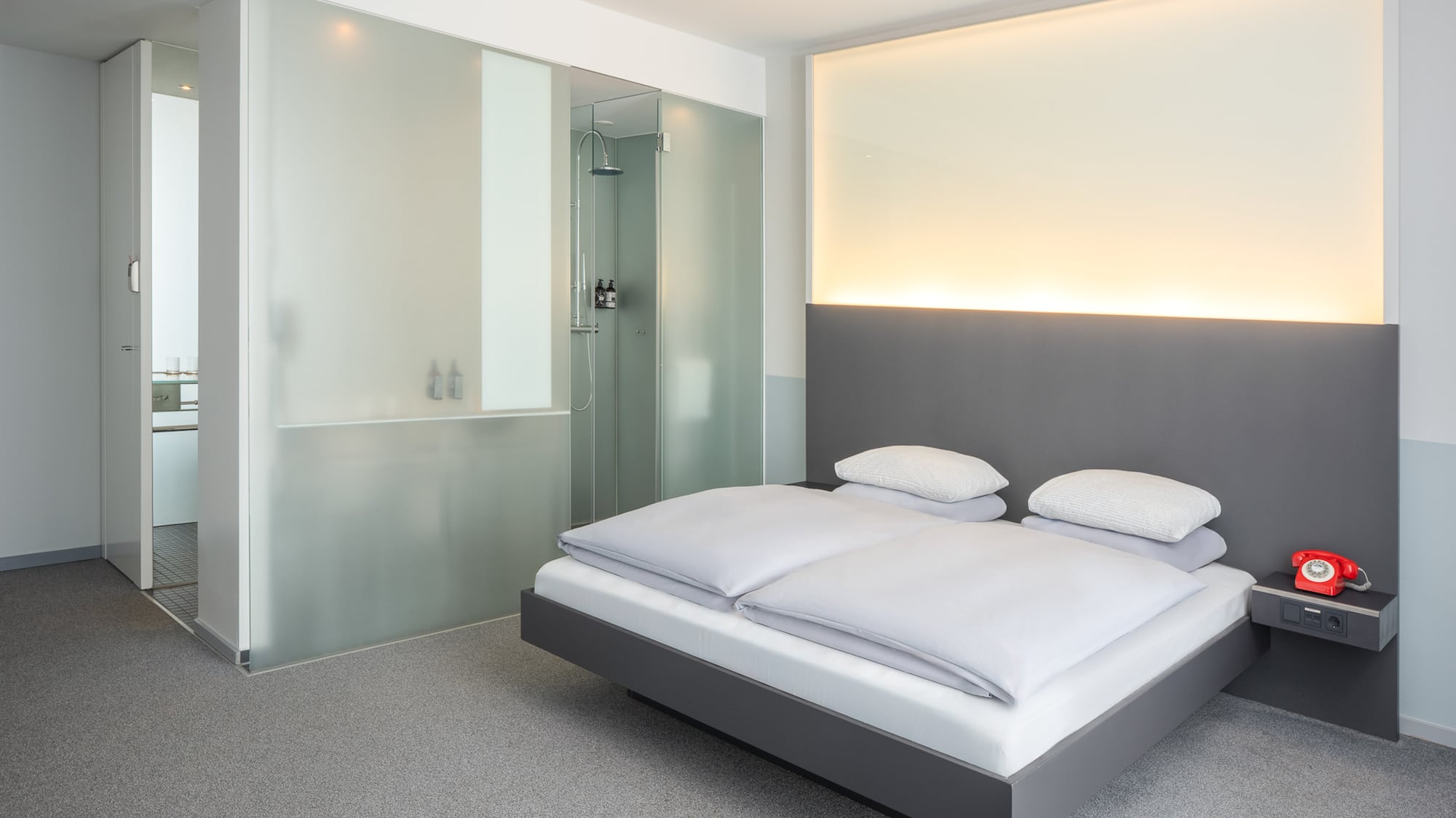 a bed with white sheets and a glass shower