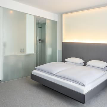 a bed with white sheets and a glass shower