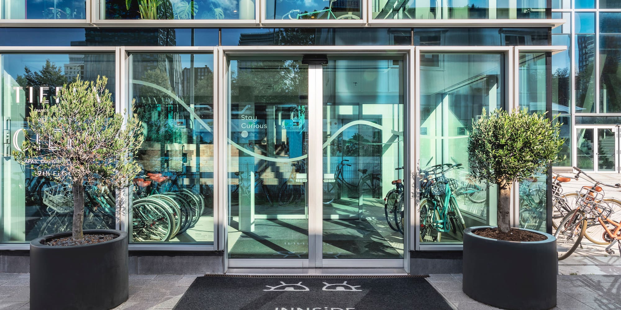 a glass door with a sign and trees in front of it