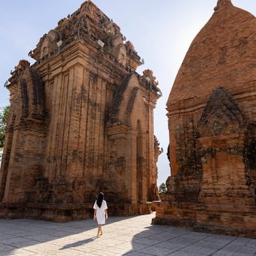 a woman walking in front of a brick structure