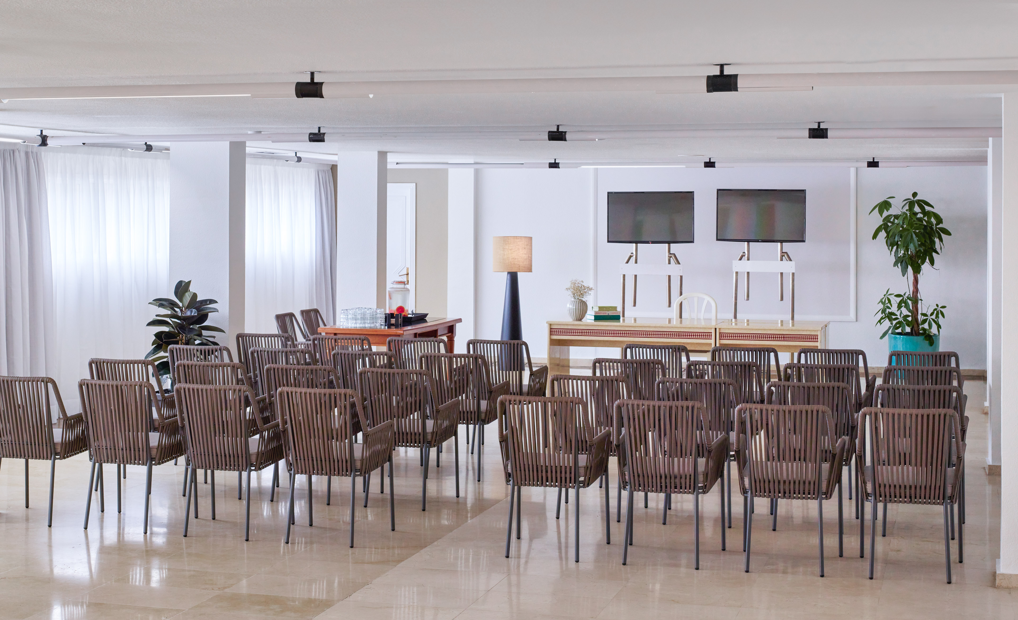 Modern conference room with chairs, dual screens, and refreshment area.