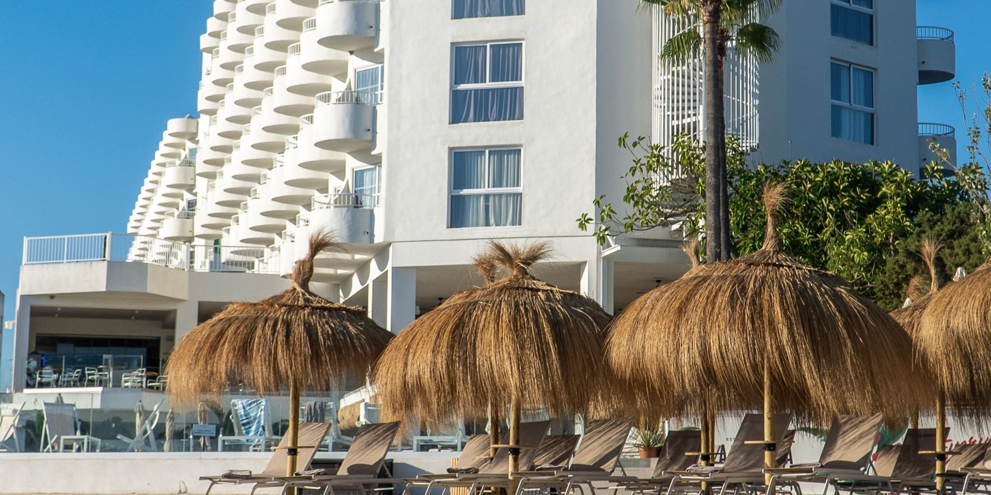 a group of straw umbrellas on a beach next to a white building