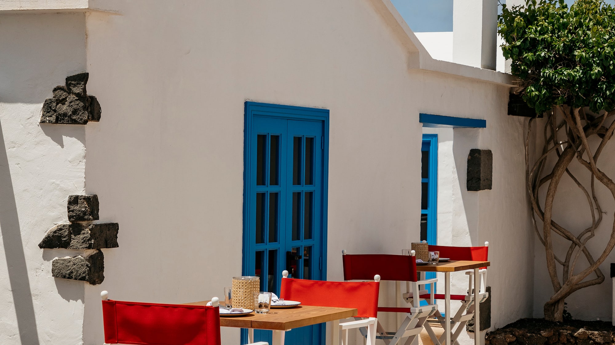 a white building with red chairs and tables outside