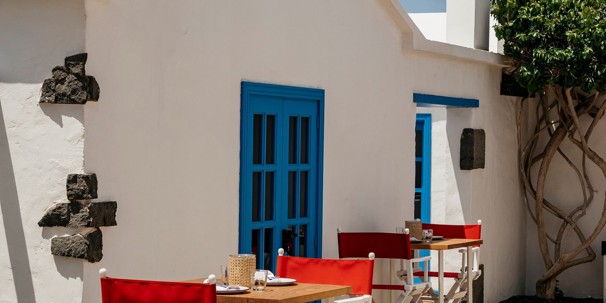 a white building with red chairs and tables outside
