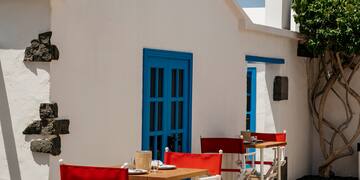 a white building with red chairs and tables outside