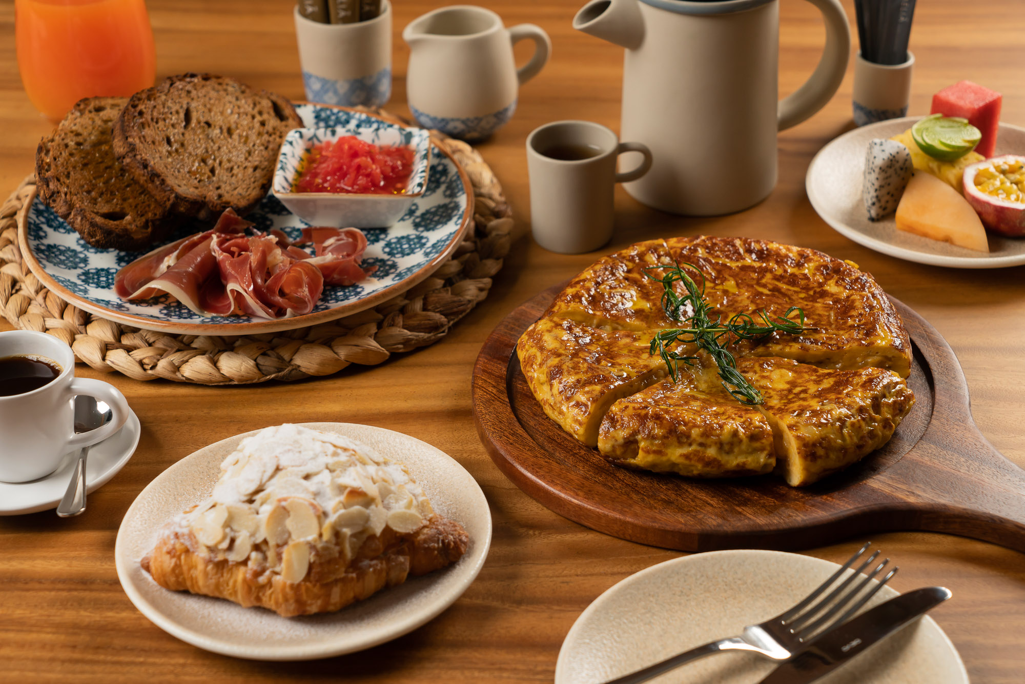 Hearty breakfast: Spanish tortilla, almond croissant, prosciutto, toast, coffee, fruit.