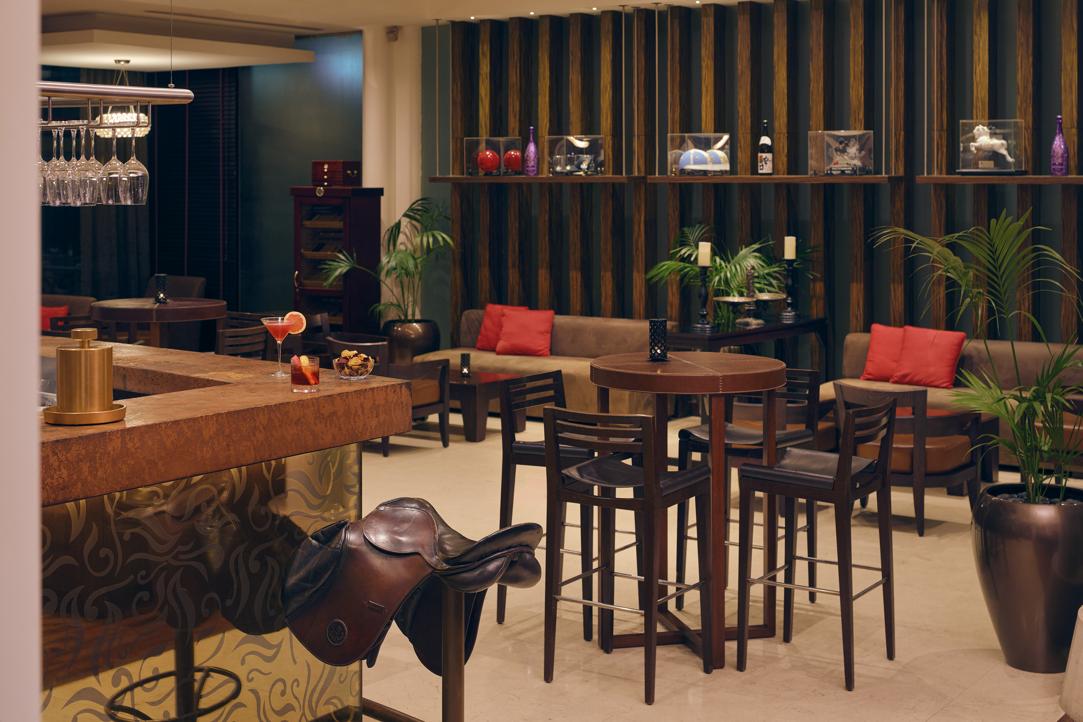 Bar lounge elegante con barra, cócteles, sofás y silla de montar de cuero.