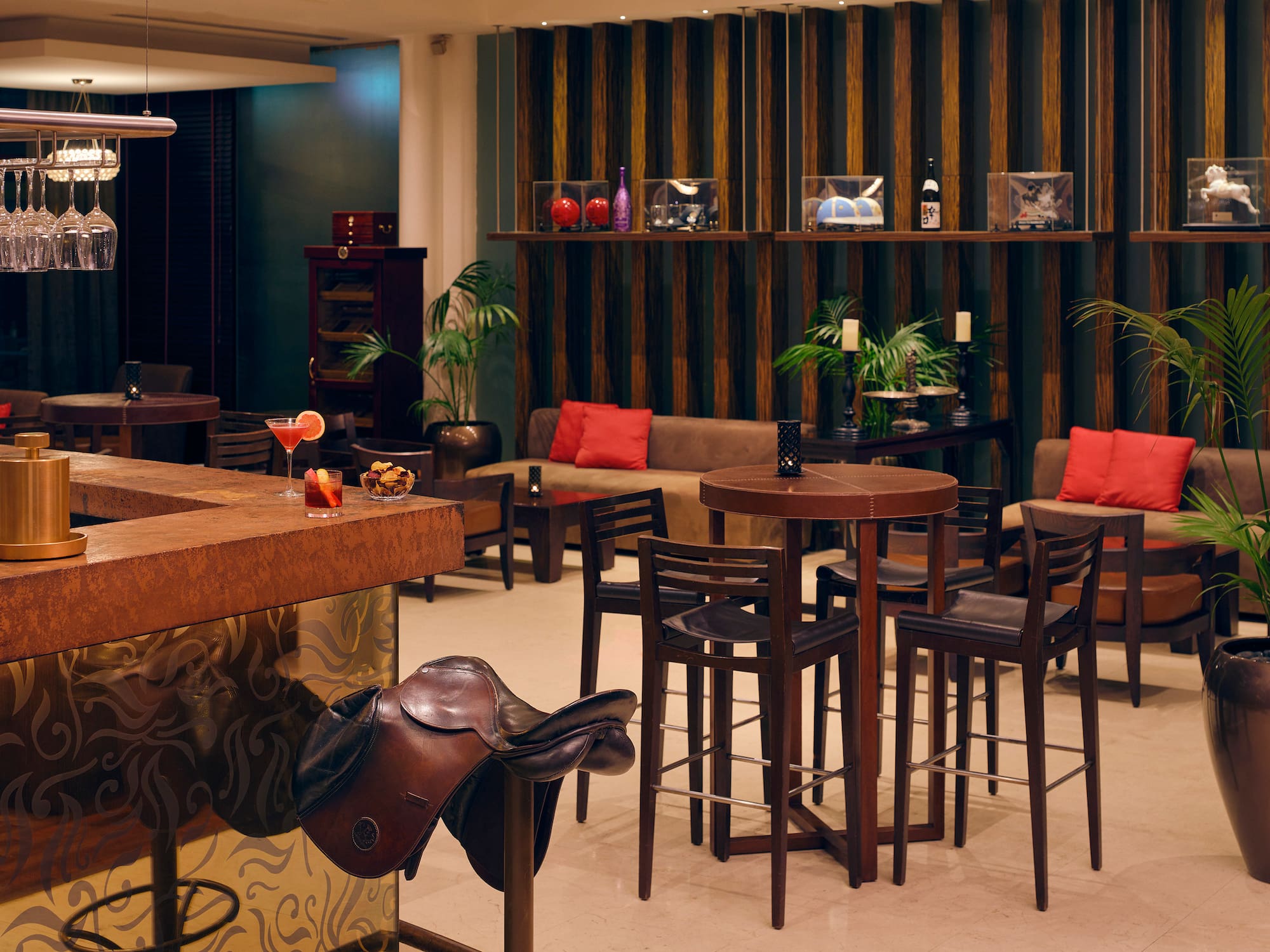Bar lounge elegante con barra, cócteles, sofás y silla de montar de cuero.