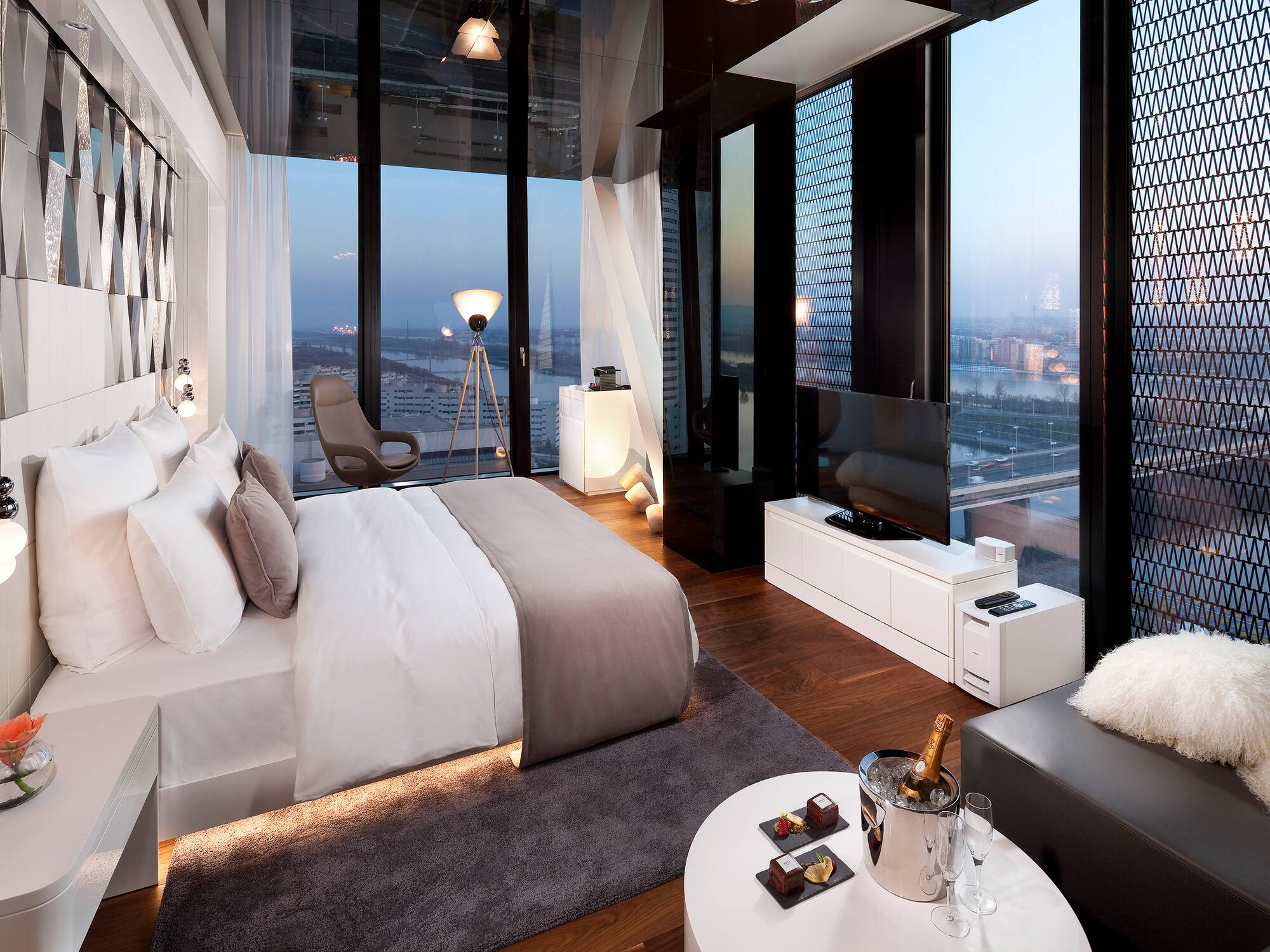 Stylish hotel room with floor-to-ceiling windows, city skyline, and modern design.