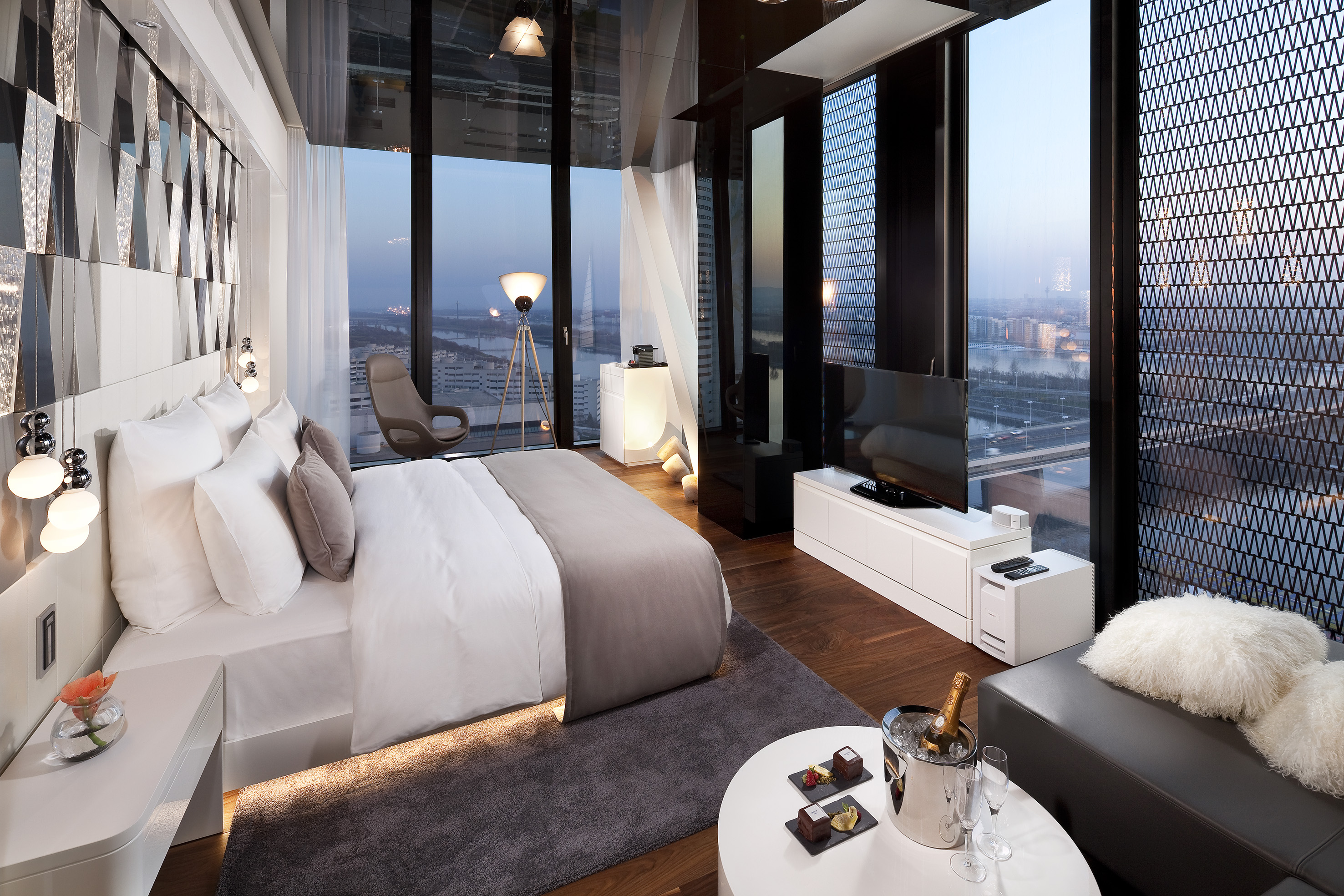 Stylish hotel room with floor-to-ceiling windows, city skyline, and modern design.