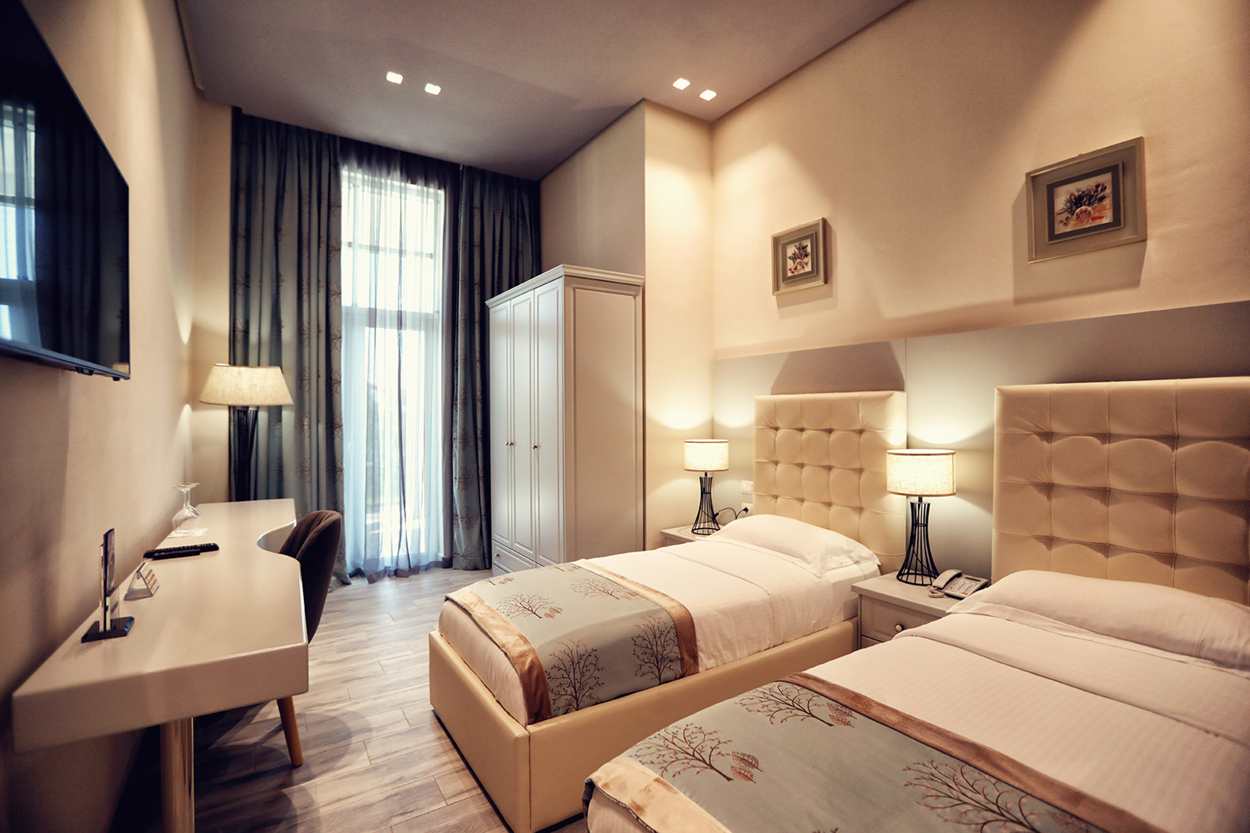 Modern hotel twin room with two beds, desk, and TV.