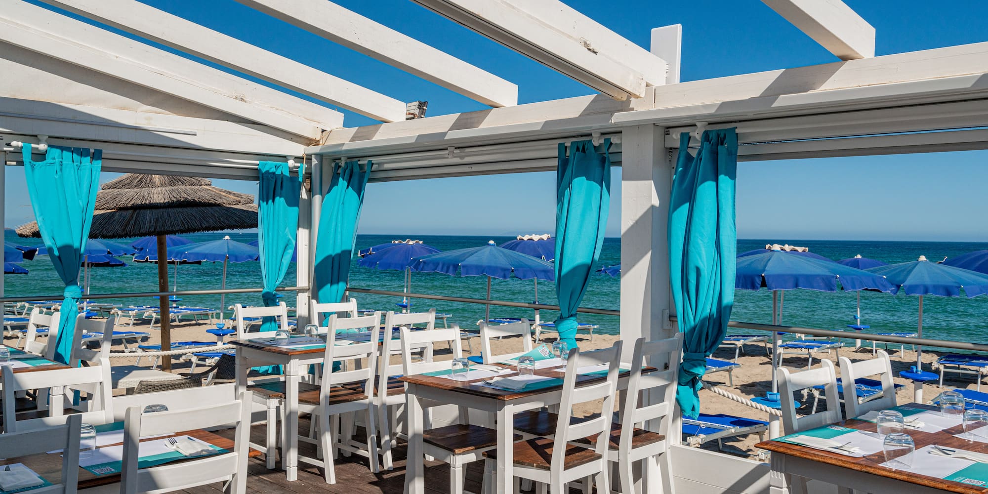 a restaurant with tables and chairs on a deck overlooking the ocean