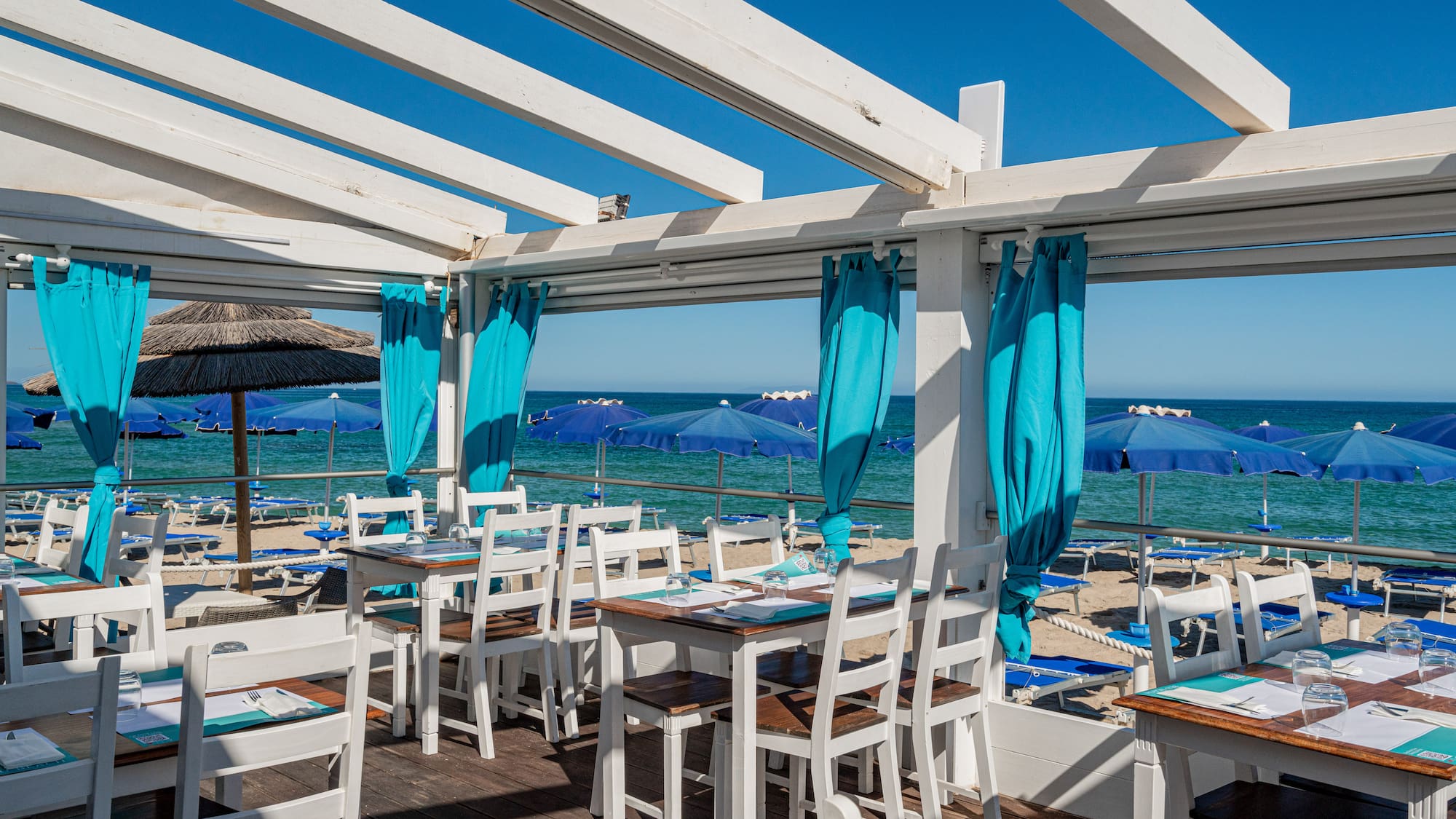 a restaurant with tables and chairs on a deck overlooking the ocean
