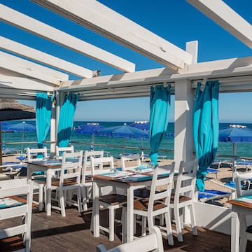 a restaurant with tables and chairs on a deck overlooking the ocean