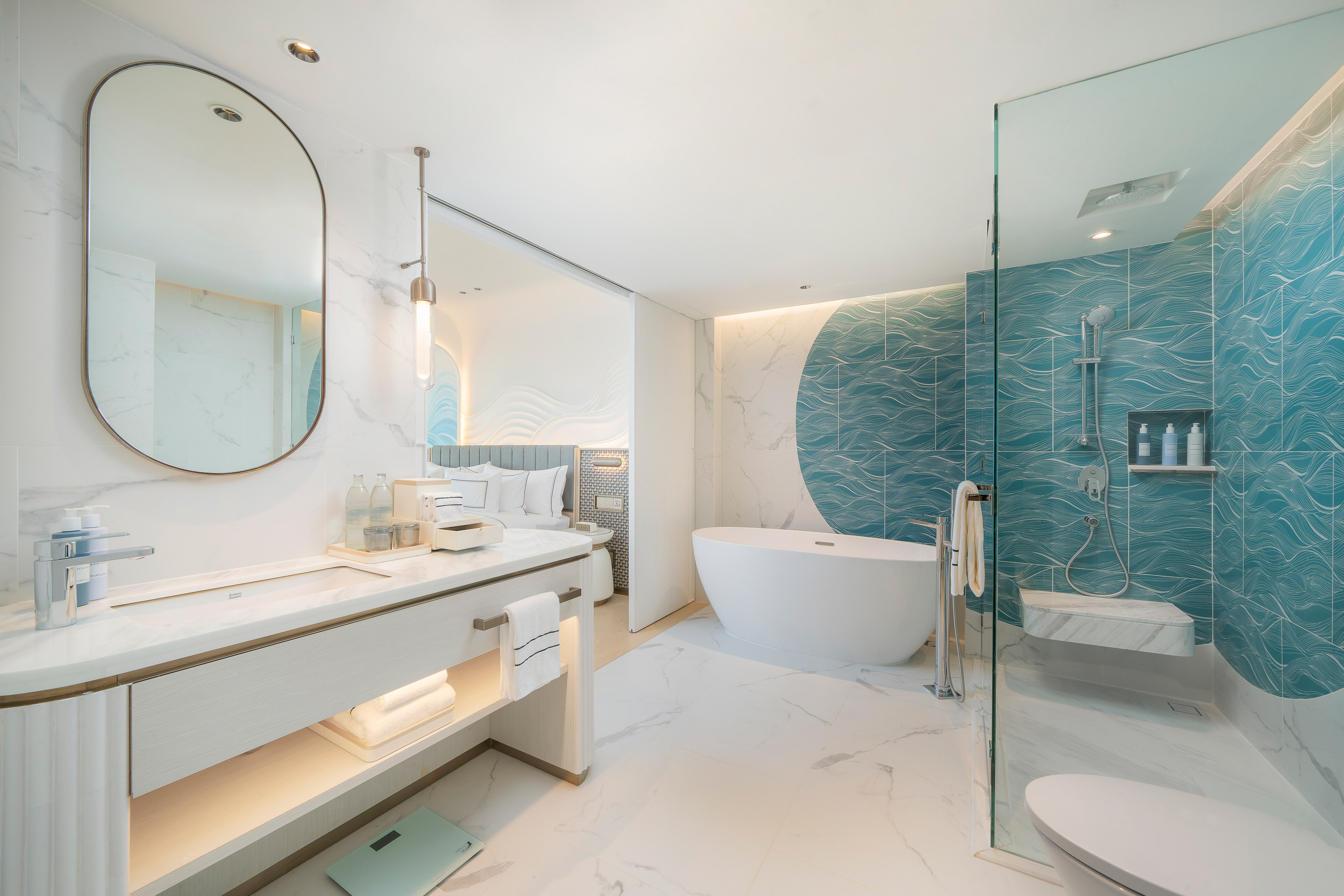 Modern hotel bathroom, freestanding tub, blue shower tiles, marble vanity.