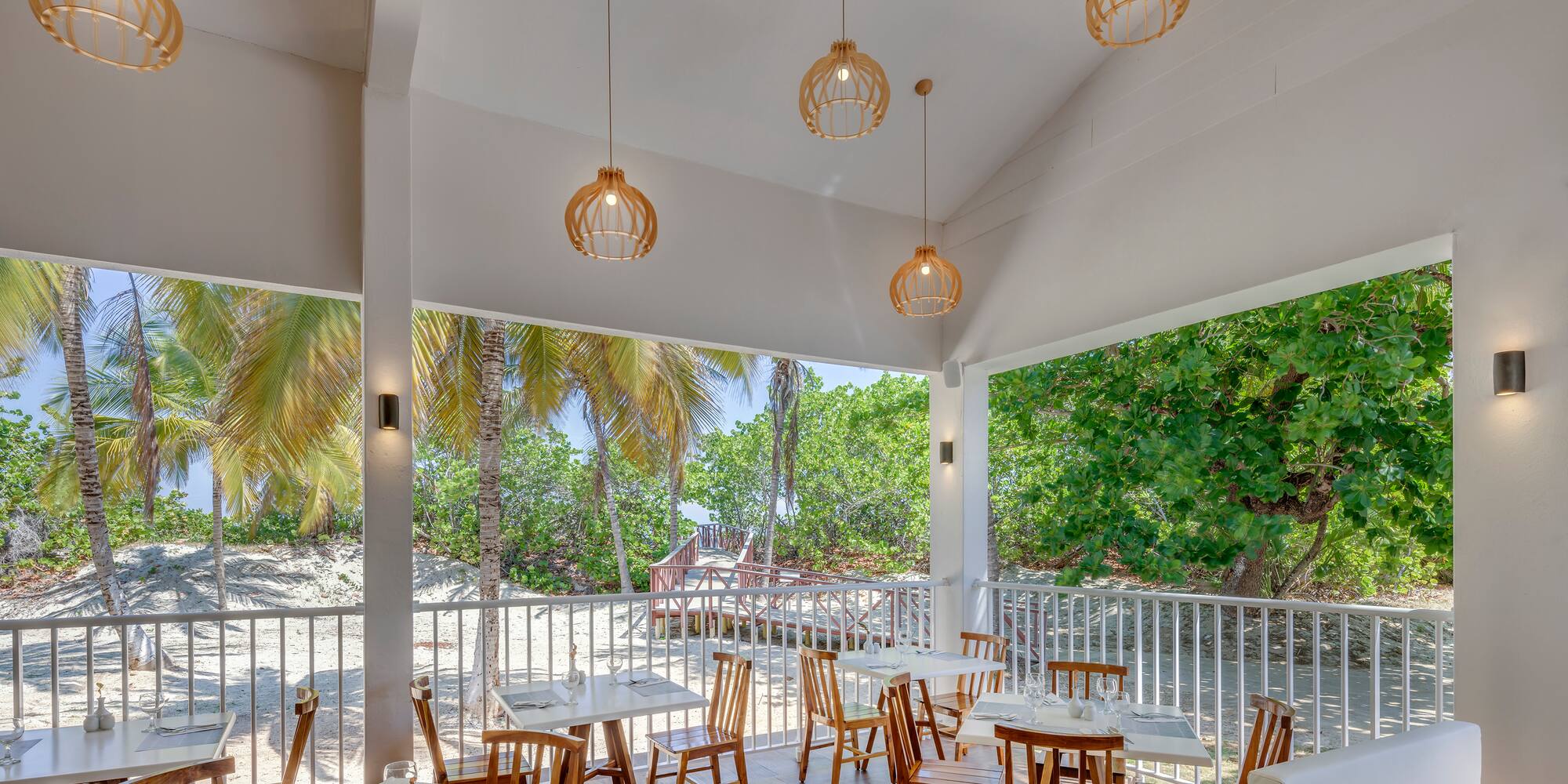 a room with tables and chairs and a white railing