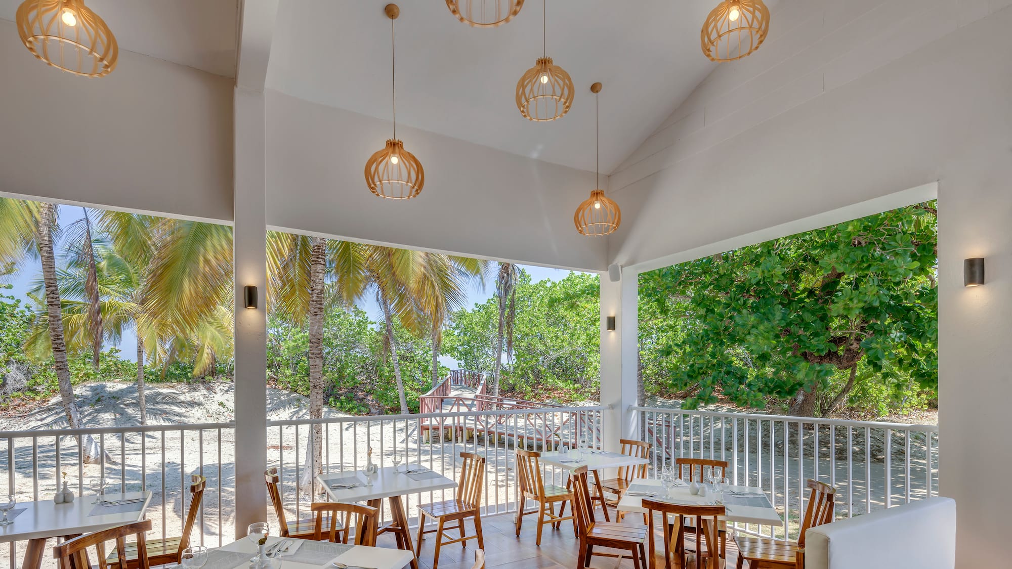 a room with tables and chairs and a white railing