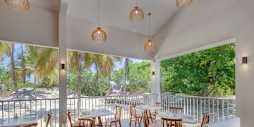a room with tables and chairs and a white railing