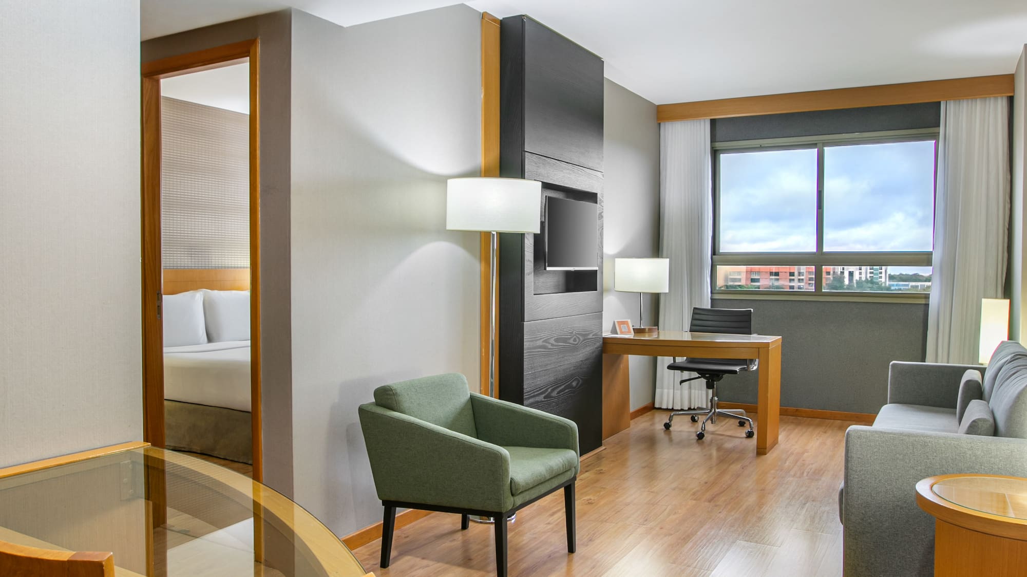 Modern hotel suite with living, dining, and bedroom areas, hardwood floors.