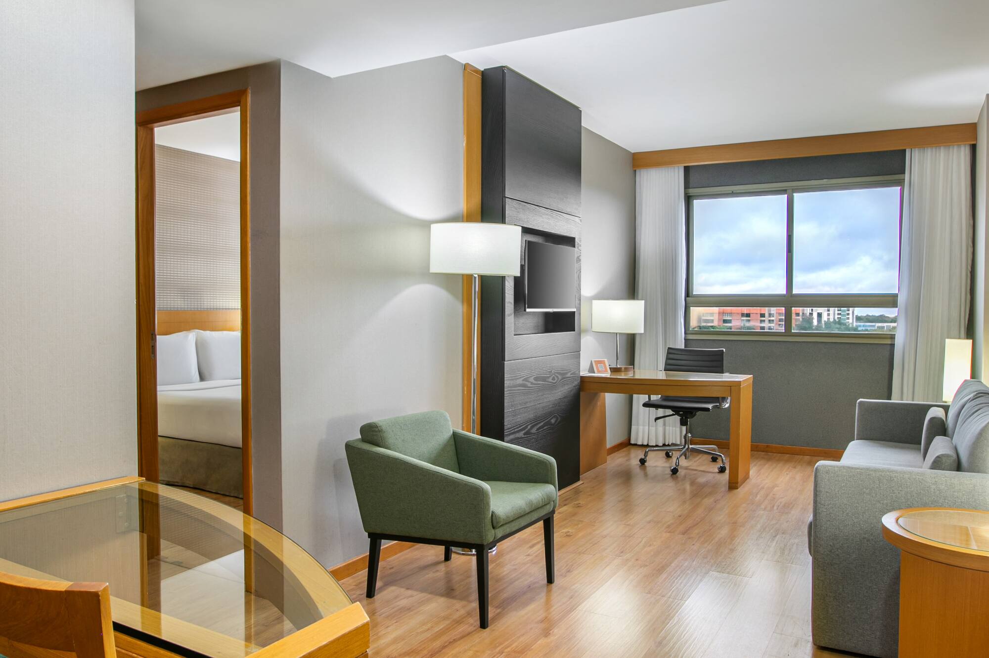 Modern hotel suite with living, dining, and bedroom areas, hardwood floors.
