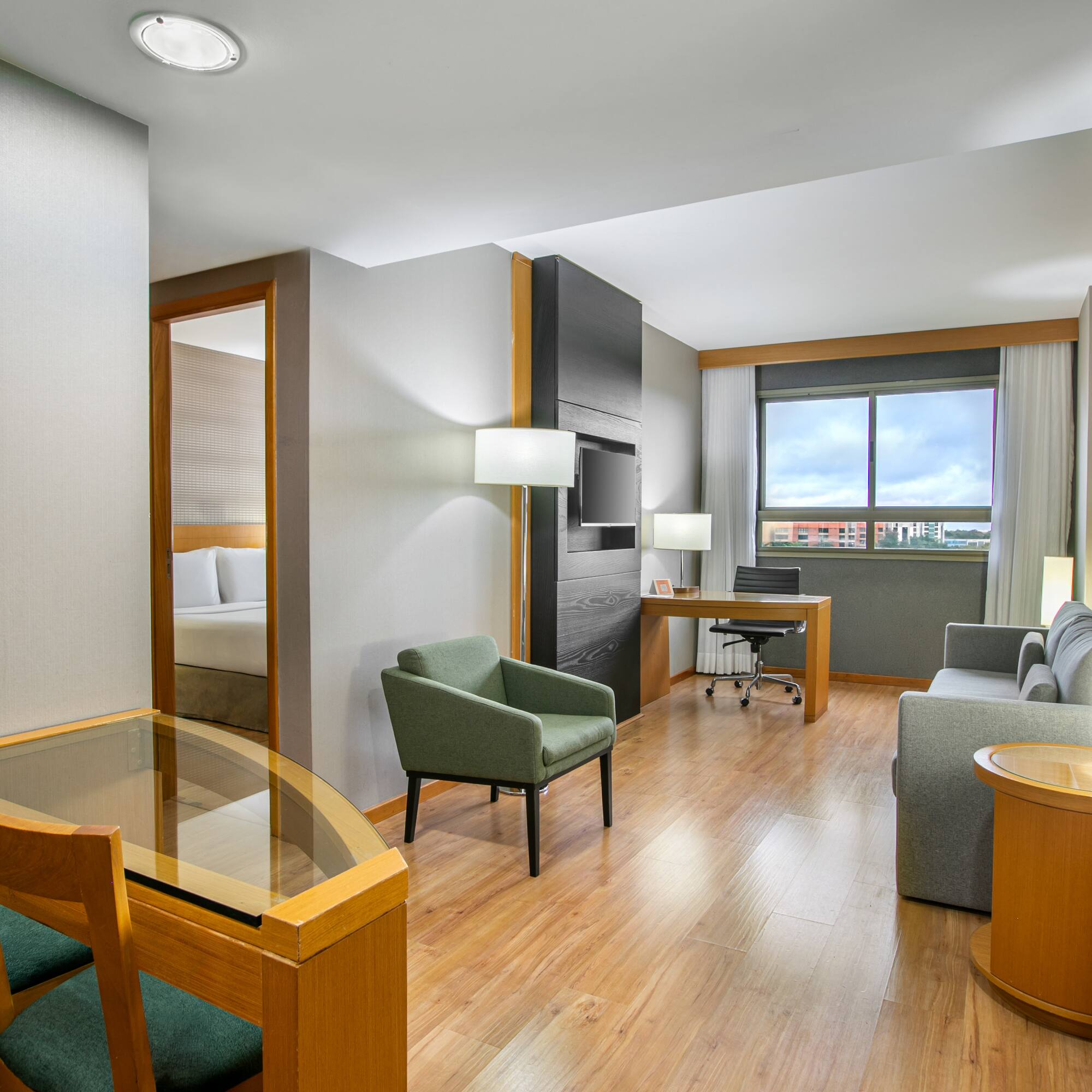 Modern hotel suite with living, dining, and bedroom areas, hardwood floors.