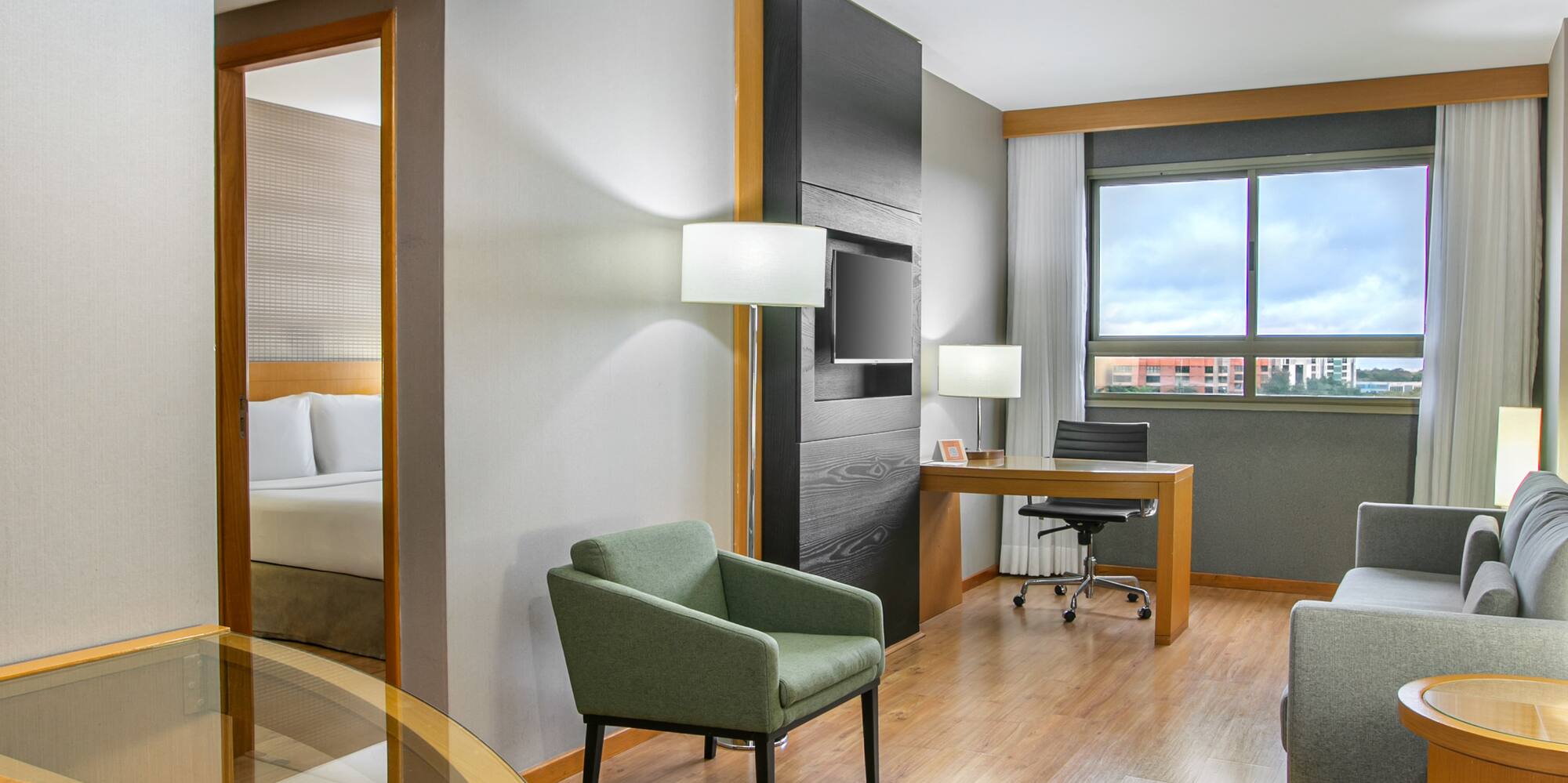 Modern hotel suite with living, dining, and bedroom areas, hardwood floors.