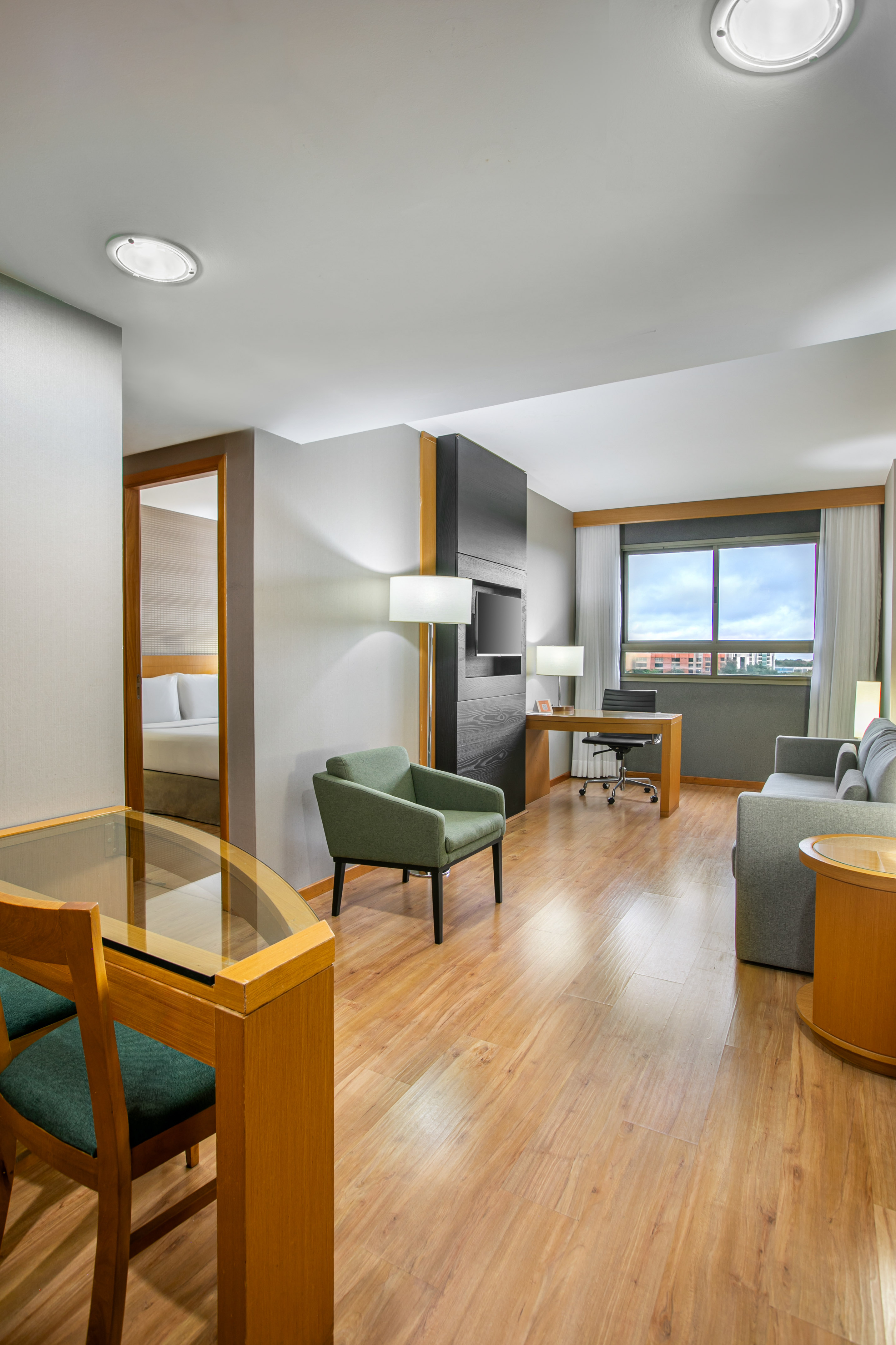 Modern hotel suite with living, dining, and bedroom areas, hardwood floors.