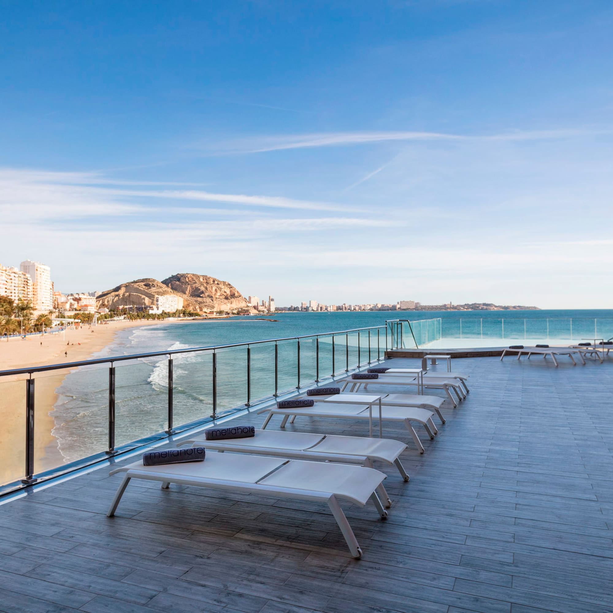 a deck with chairs and a beach in the background