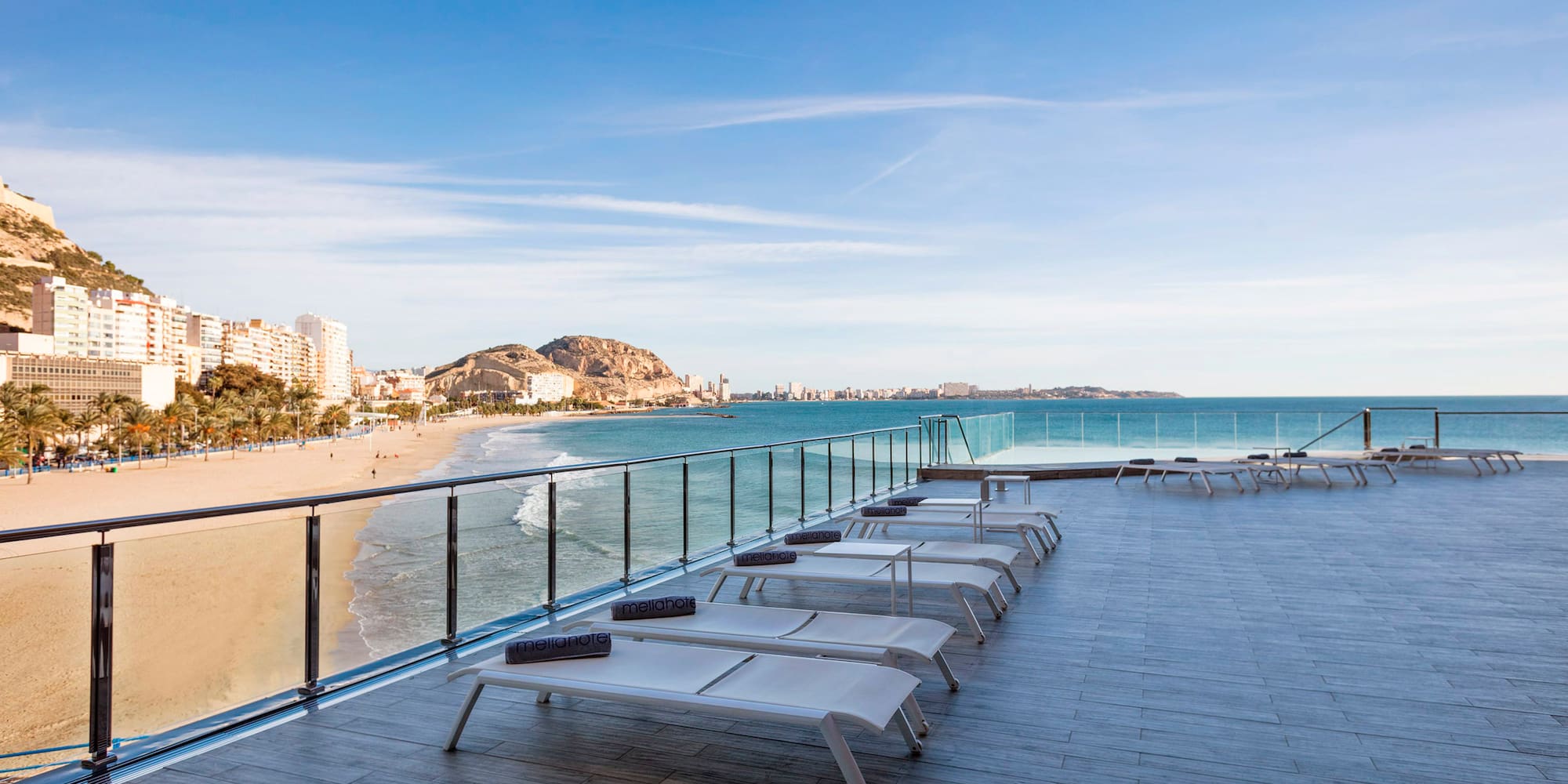 a deck with chairs and a beach in the background