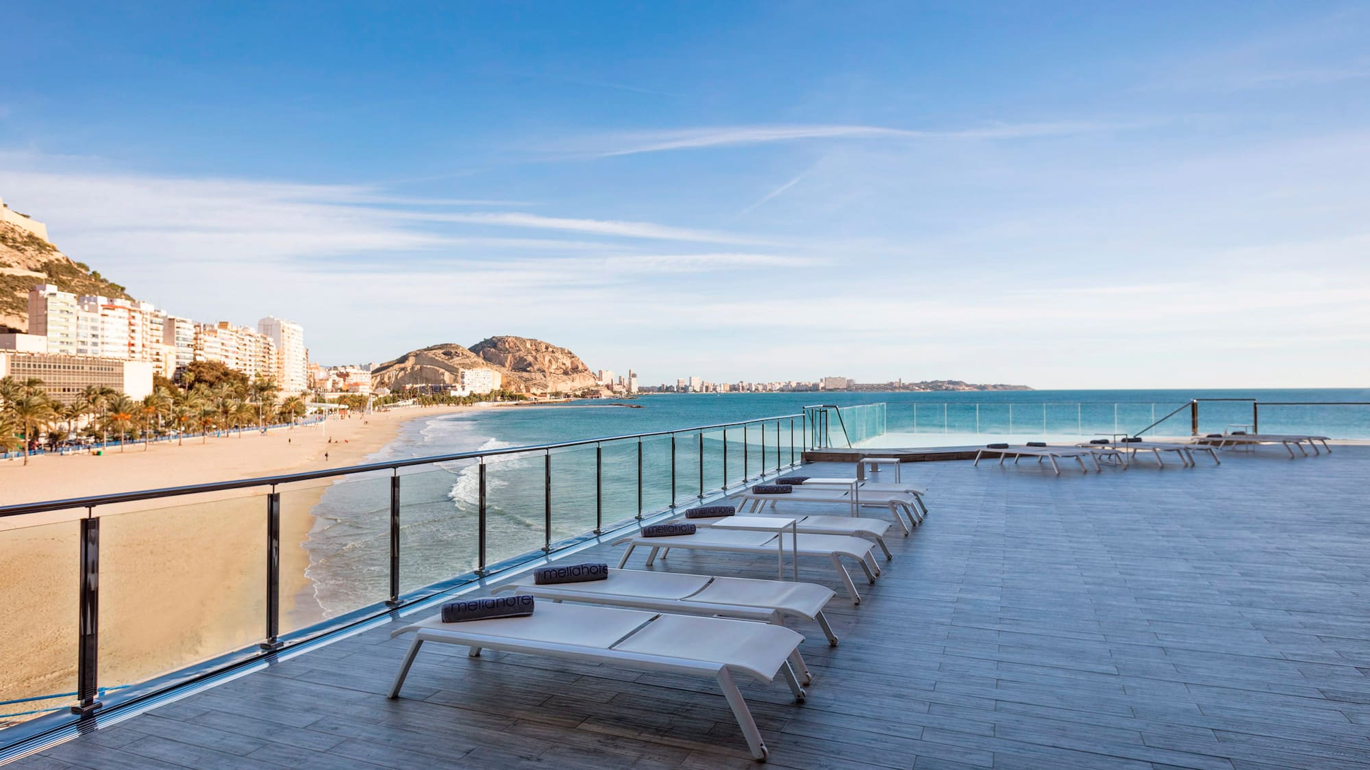 a deck with chairs and a beach in the background