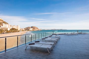 a deck with chairs and a beach in the background