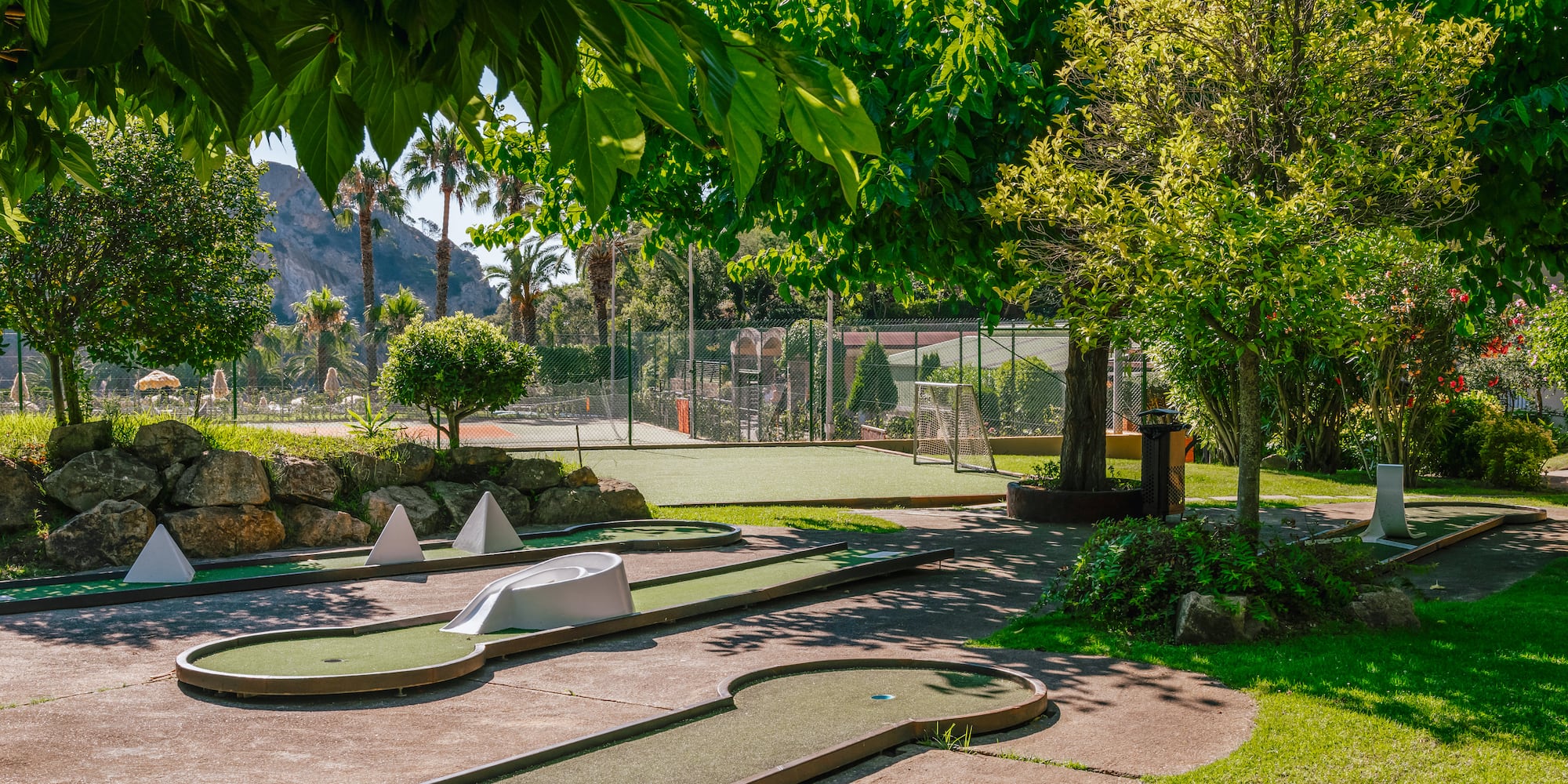 a mini golf course with trees and a fence