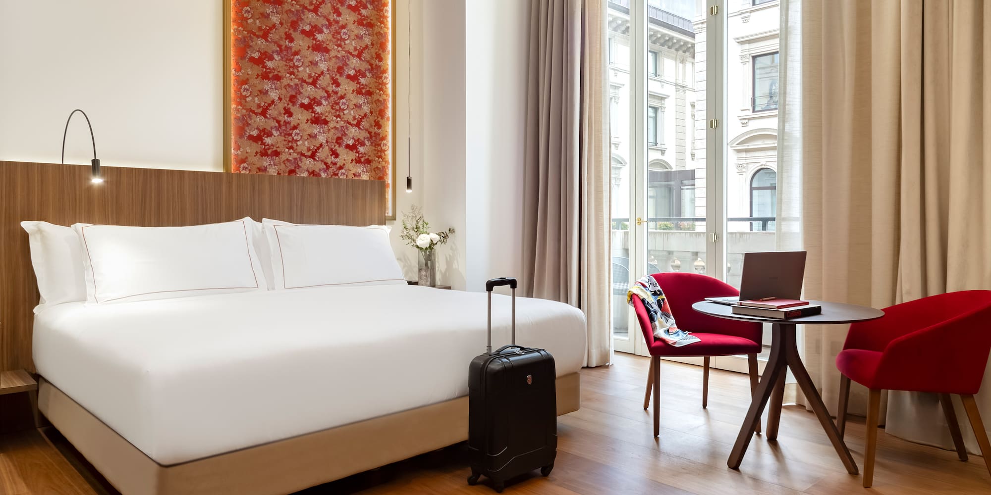 Milan city views from the Premier room with Balcony with a bed and a chair and a laptop at the Palazzo Cordusio Gran Melia