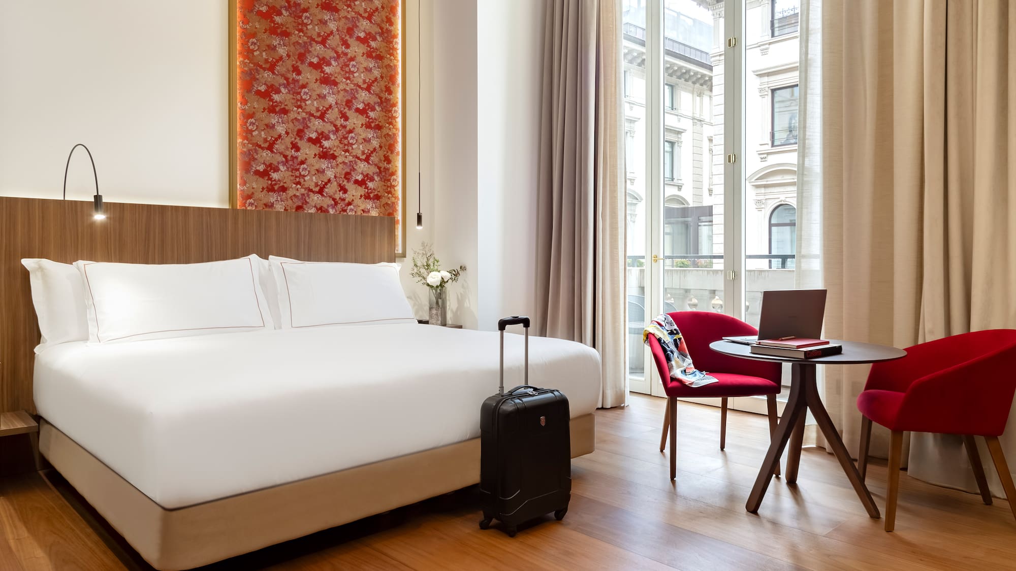 Milan city views from the Premier room with Balcony with a bed and a chair and a laptop at the Palazzo Cordusio Gran Melia