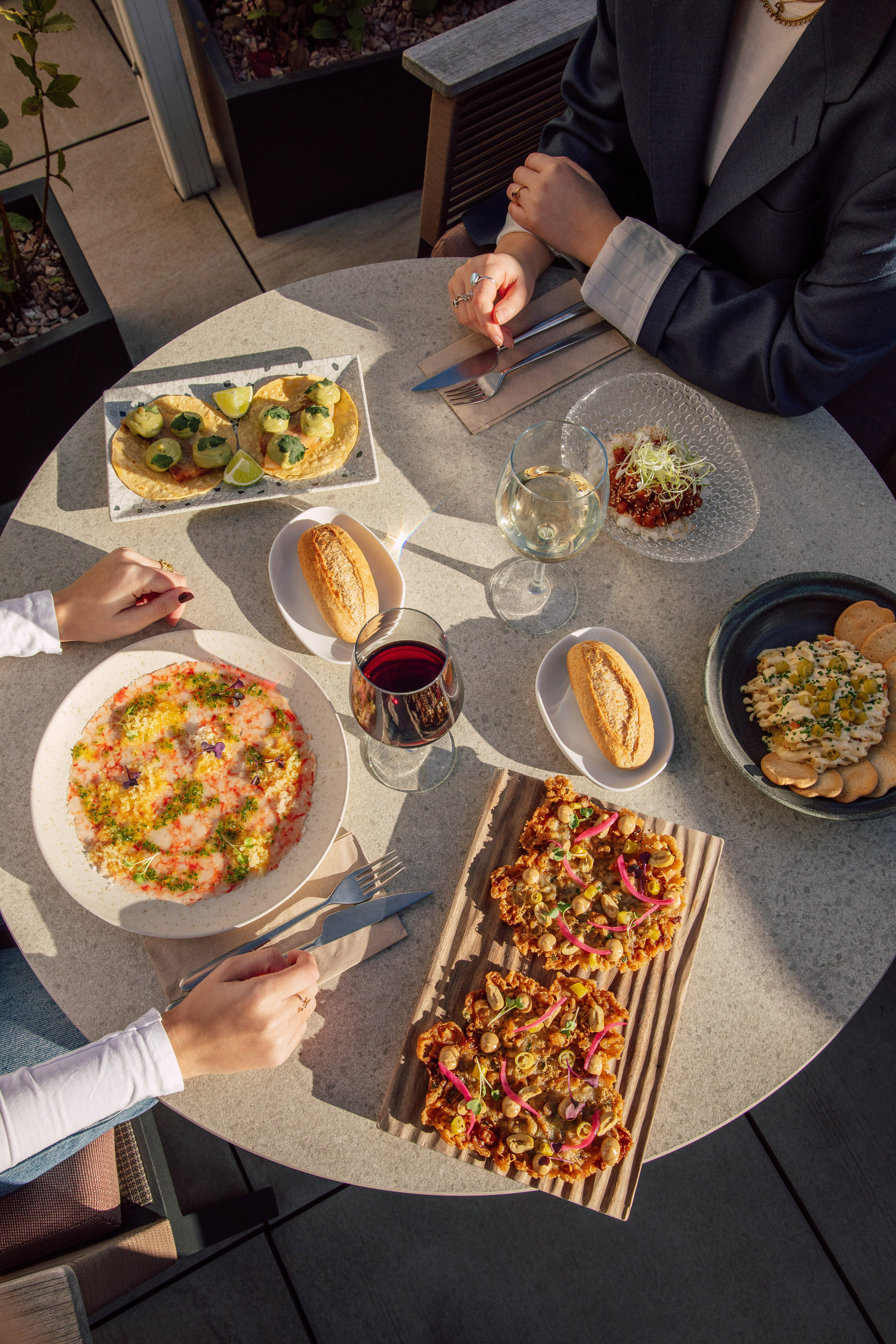 Gourmet tapas and wine on an outdoor table with two diners.