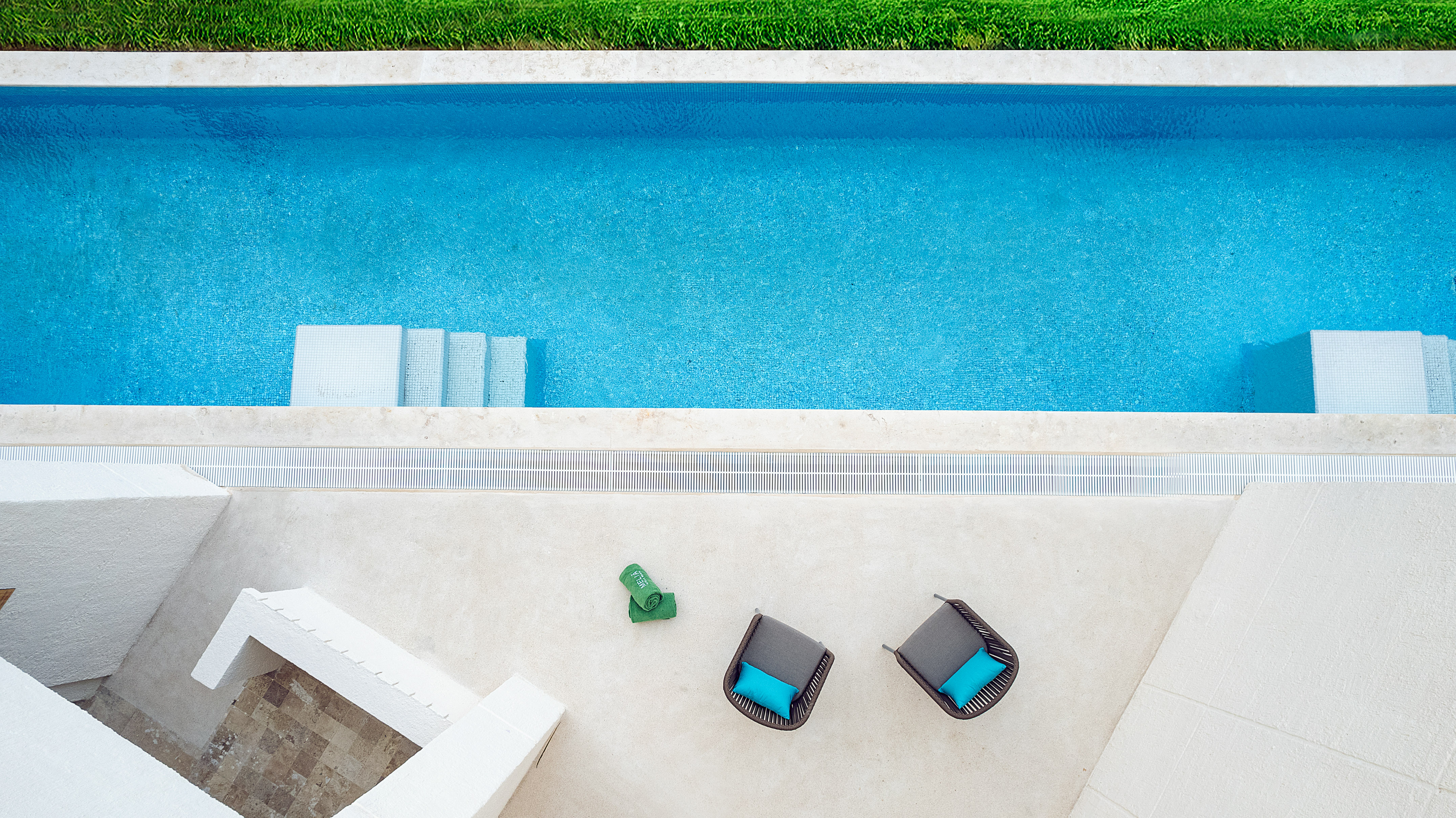Modern outdoor swimming pool with lounge chairs on a white patio.